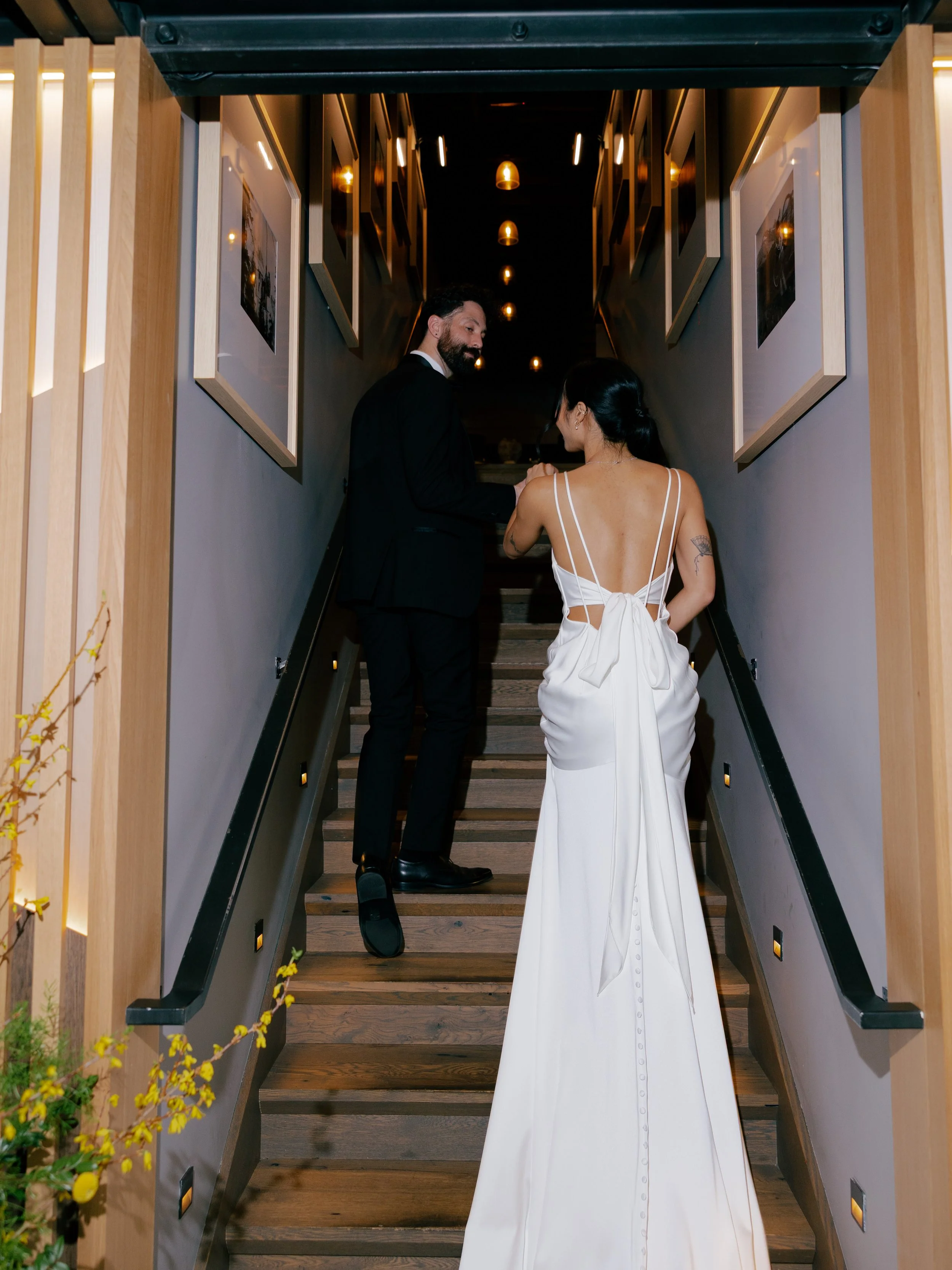 groom-leading-bride-upstairs-as-her-silk-wedding-dress-flows-behind.jpg