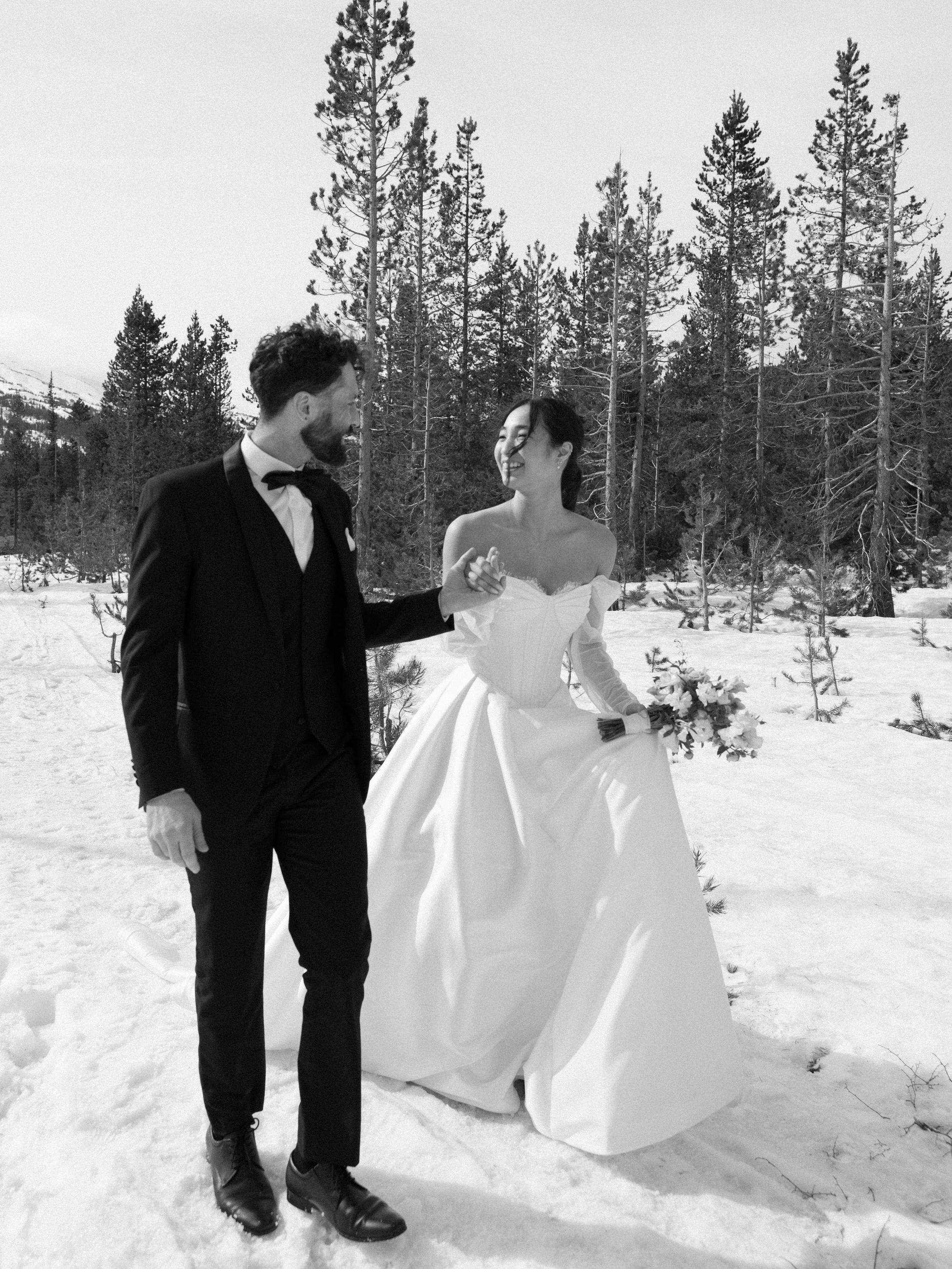groom-holding-brides-hand-leading-her-through-snow-covered-woods.jpg