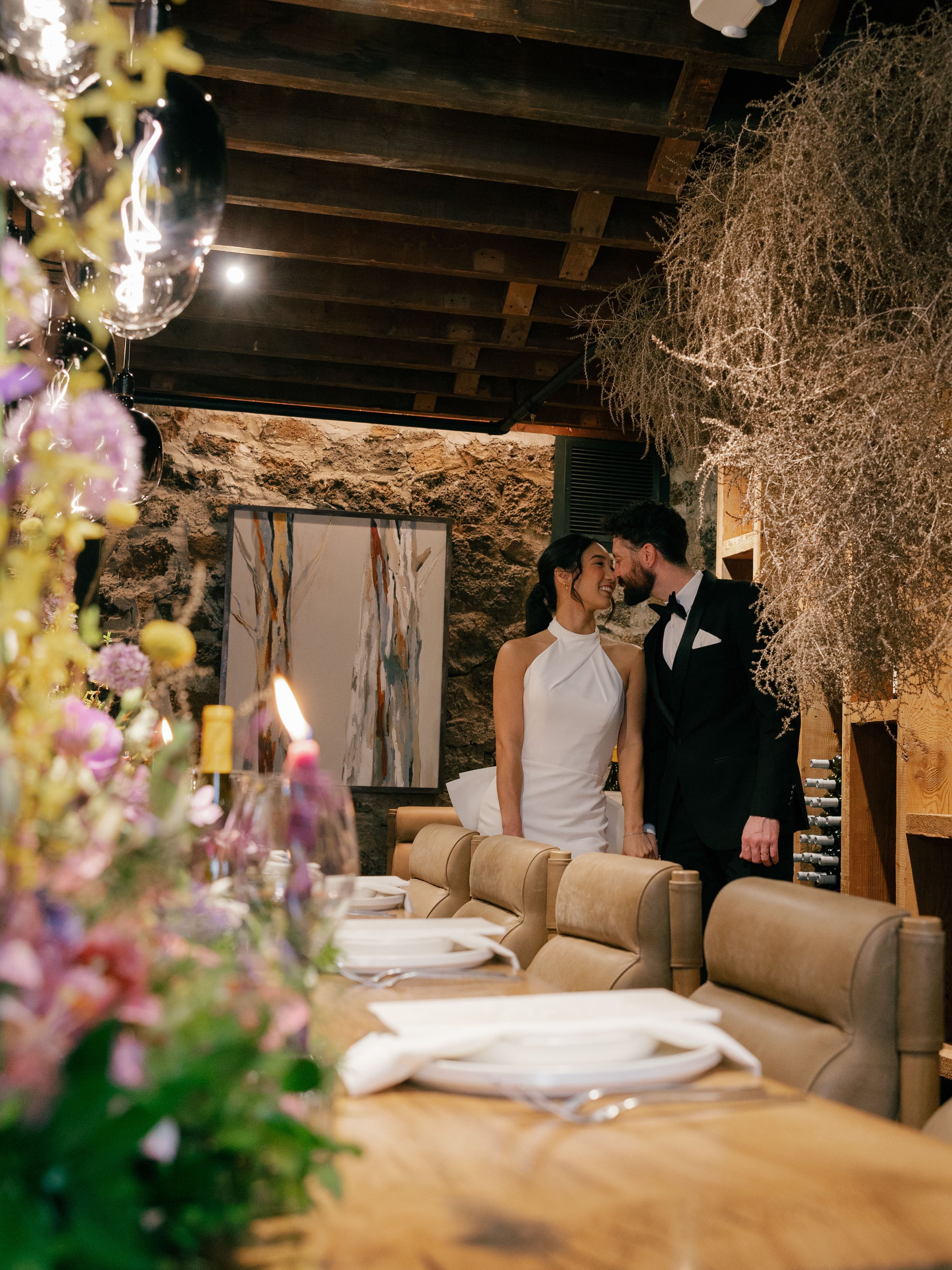 bride-and-groom-kissing-behind-set-wedding-table.jpg