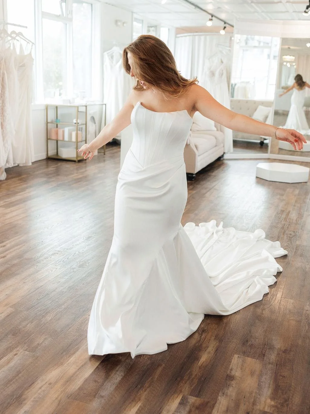 Happy bride walking with arms open wide showing off her sleek satin wedding dress