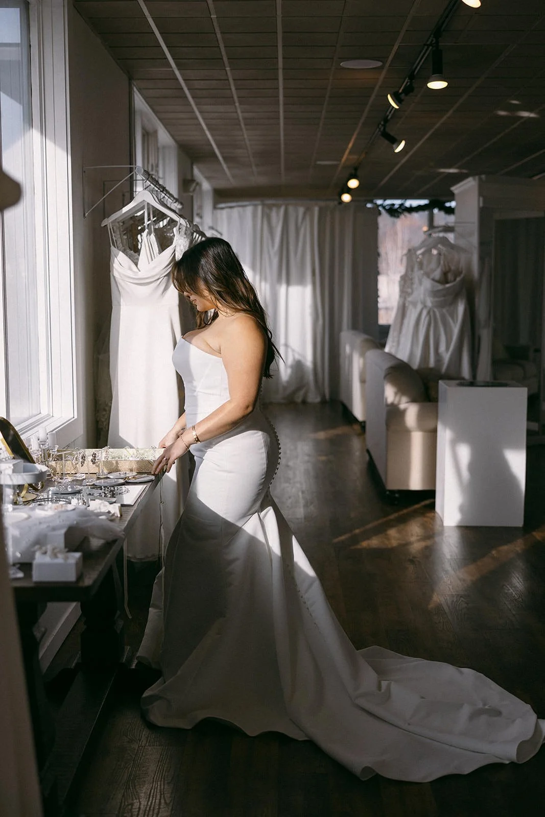 bride wearing fitted satin wedding dress looking at a jewelry table