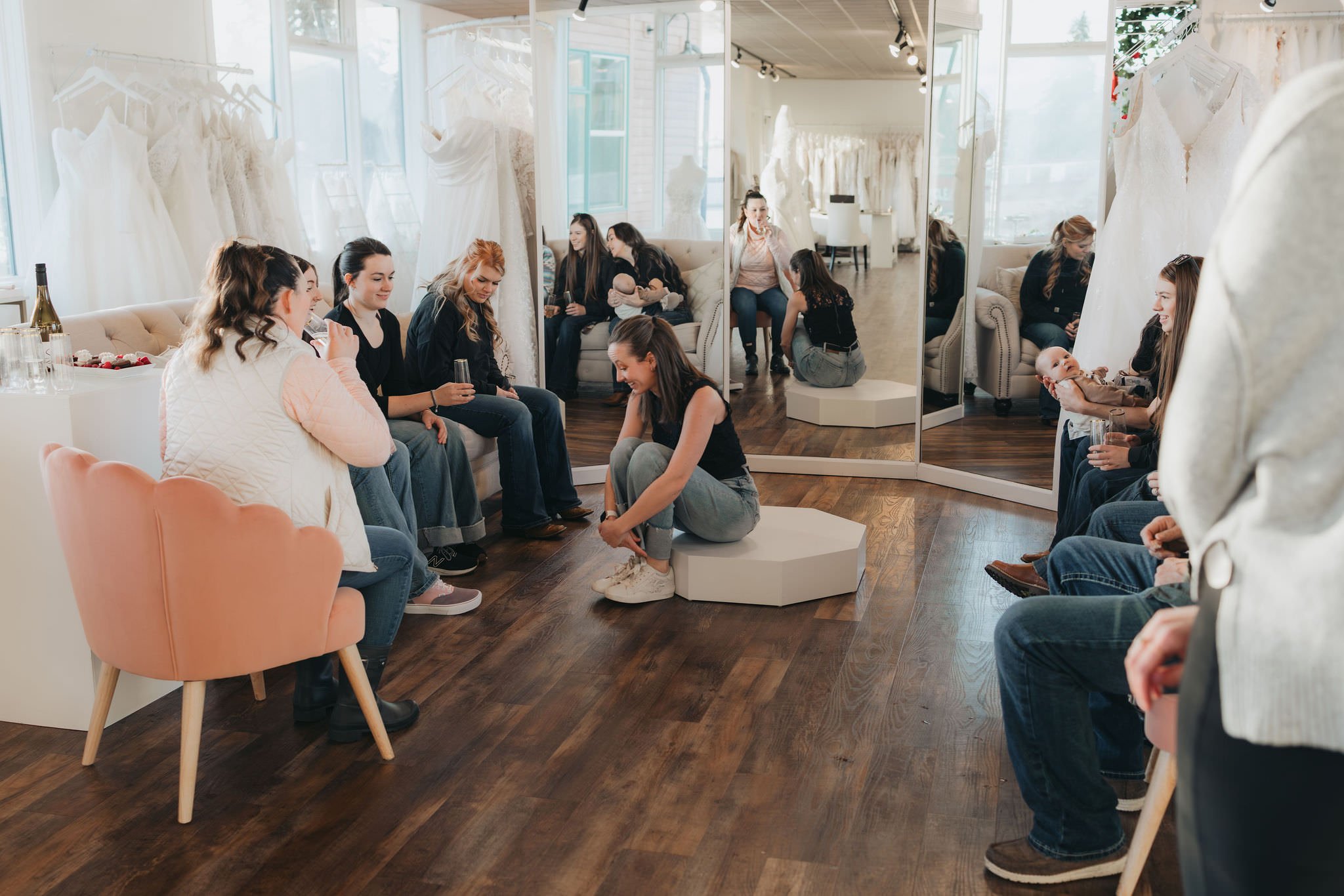 bridal stylist chatting with a bride group about dress inspiration while they laugh and drink champagne