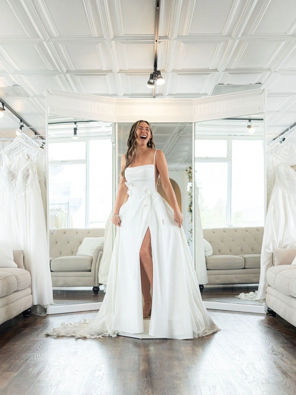 Joyful bride standing on a pedestal playfully laughing and revealing the leg slit in her dress