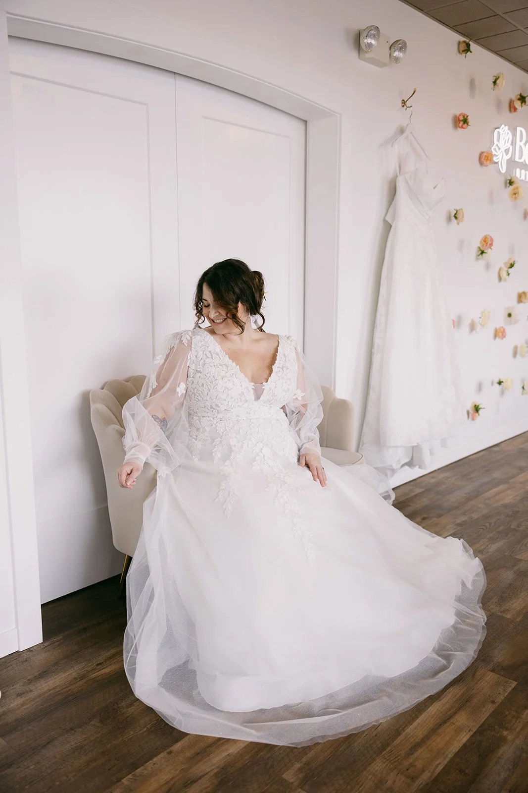 bride in tulle sleeved wedding dress sitting on a beige couch