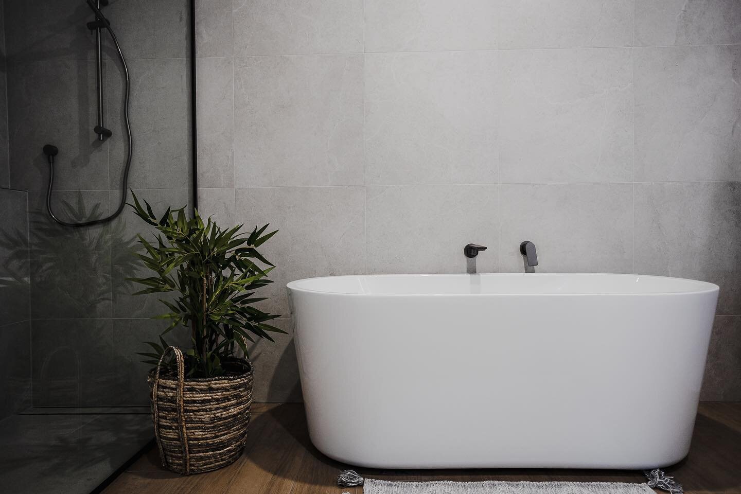 Introducing the stunning centerpiece of this bathroom - the bathtub! Perfect for ultimate relaxation and unwinding after a long day. The large grey tiles on the walls and wood-look tiles on the floor give this bathroom a touch of sophistication and a