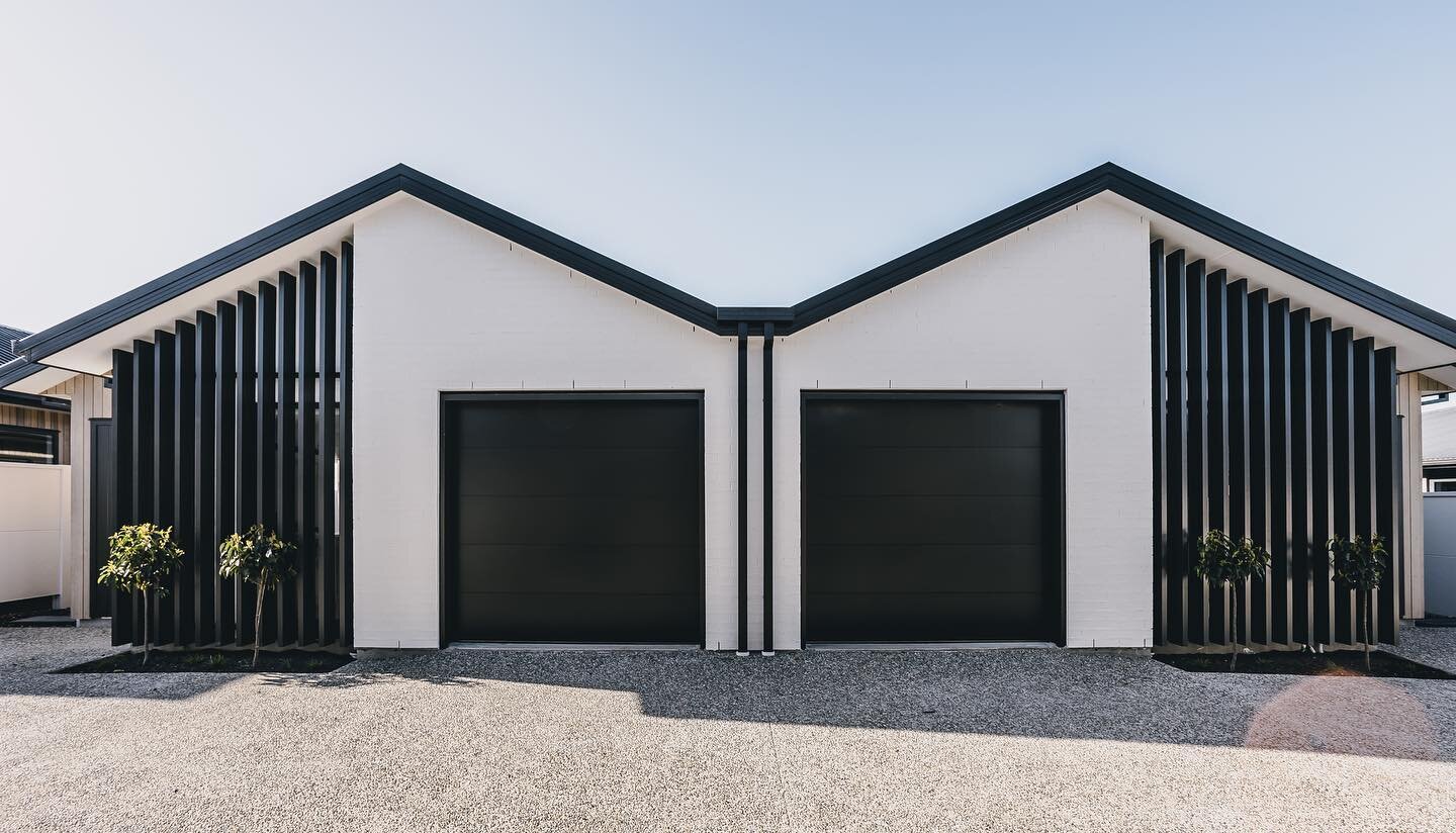A recent masterpiece from LJK Builders, featuring a stunning black, white and cedar exterior that combines sleek modern design with classic materials. The black garage doors, black spouting, black louvers and white bricks of these apartments create a