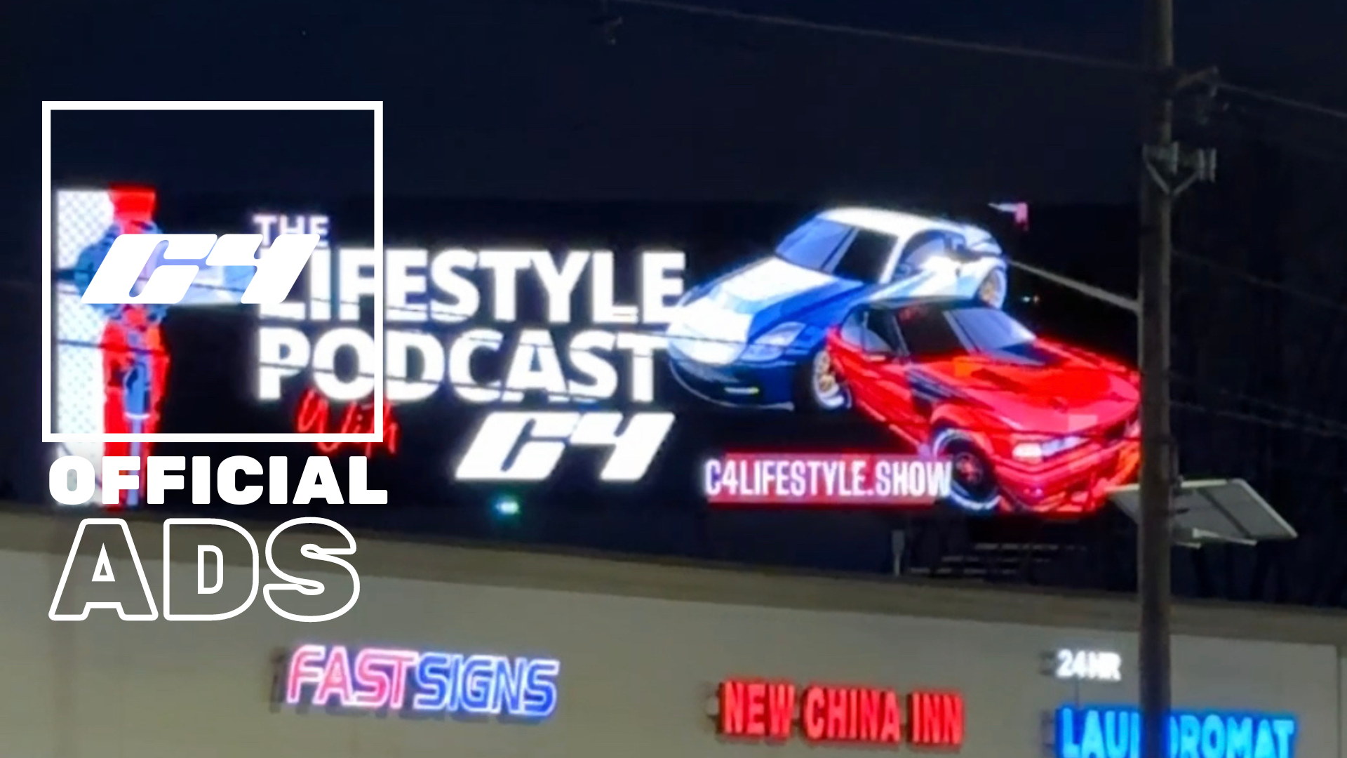 Digital billboard displaying the titles 'The C4 Lifestyle Podcast' and 'C4' with images of two sports cars, one red and one blue, on a dark background. Additional text includes 'c4lifestyle.show' and nearby signs with various phrases.
