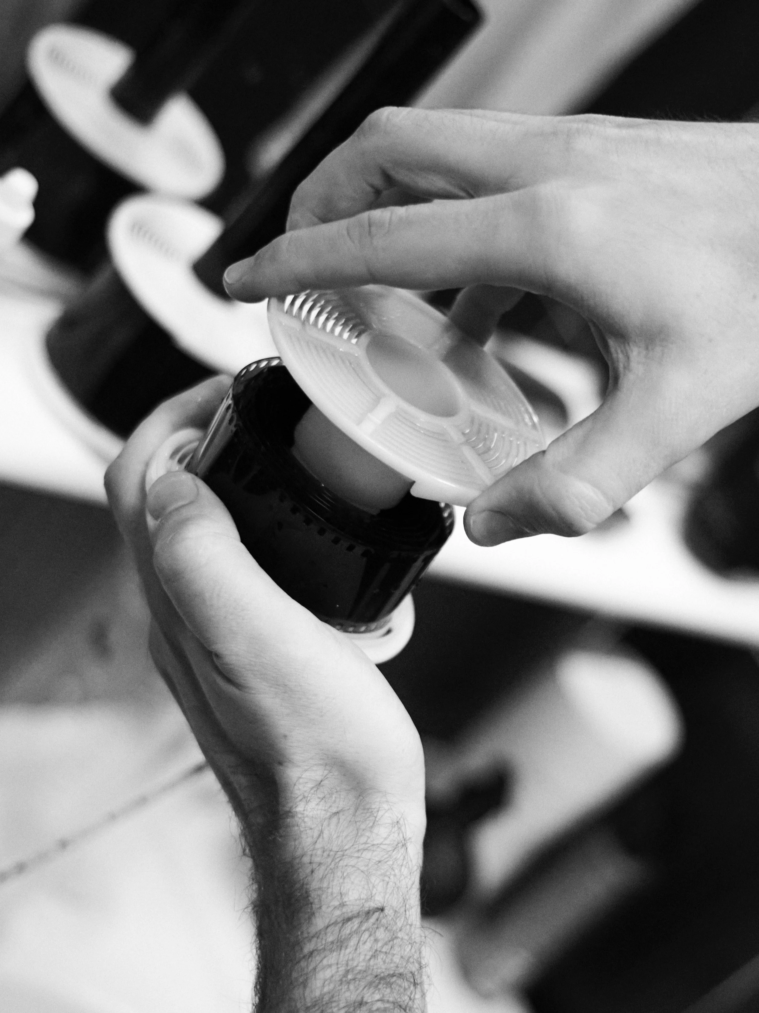 Close-up of a person’s hand holding a film developing reel in black and white.