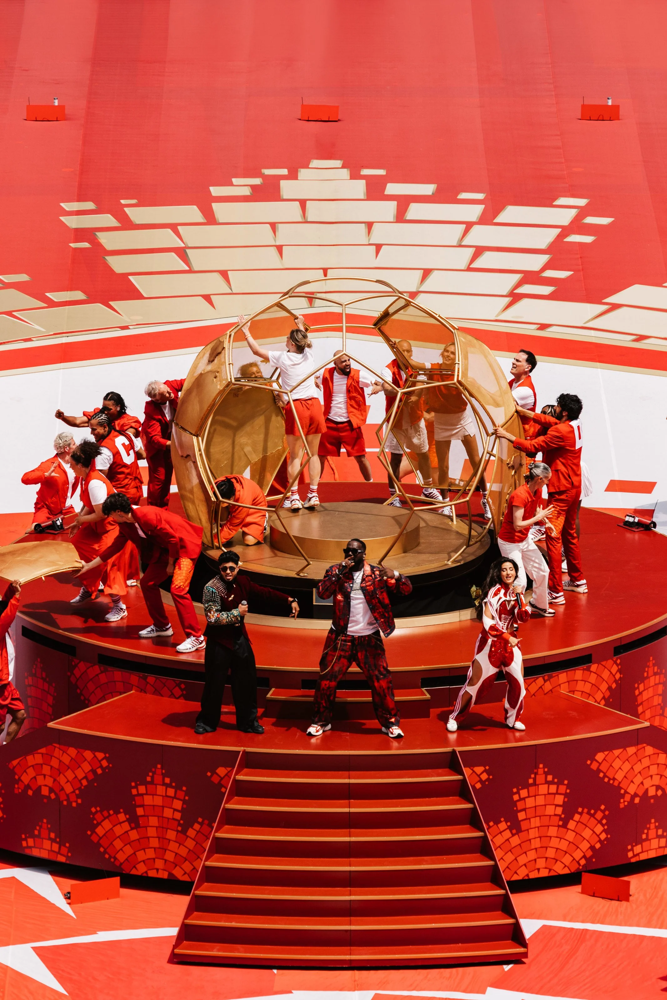 Artists constructing the golden world globe around live performers during the FIFA World Cup 2026 Toronto Opening Ceremony, designed by Ruby Law