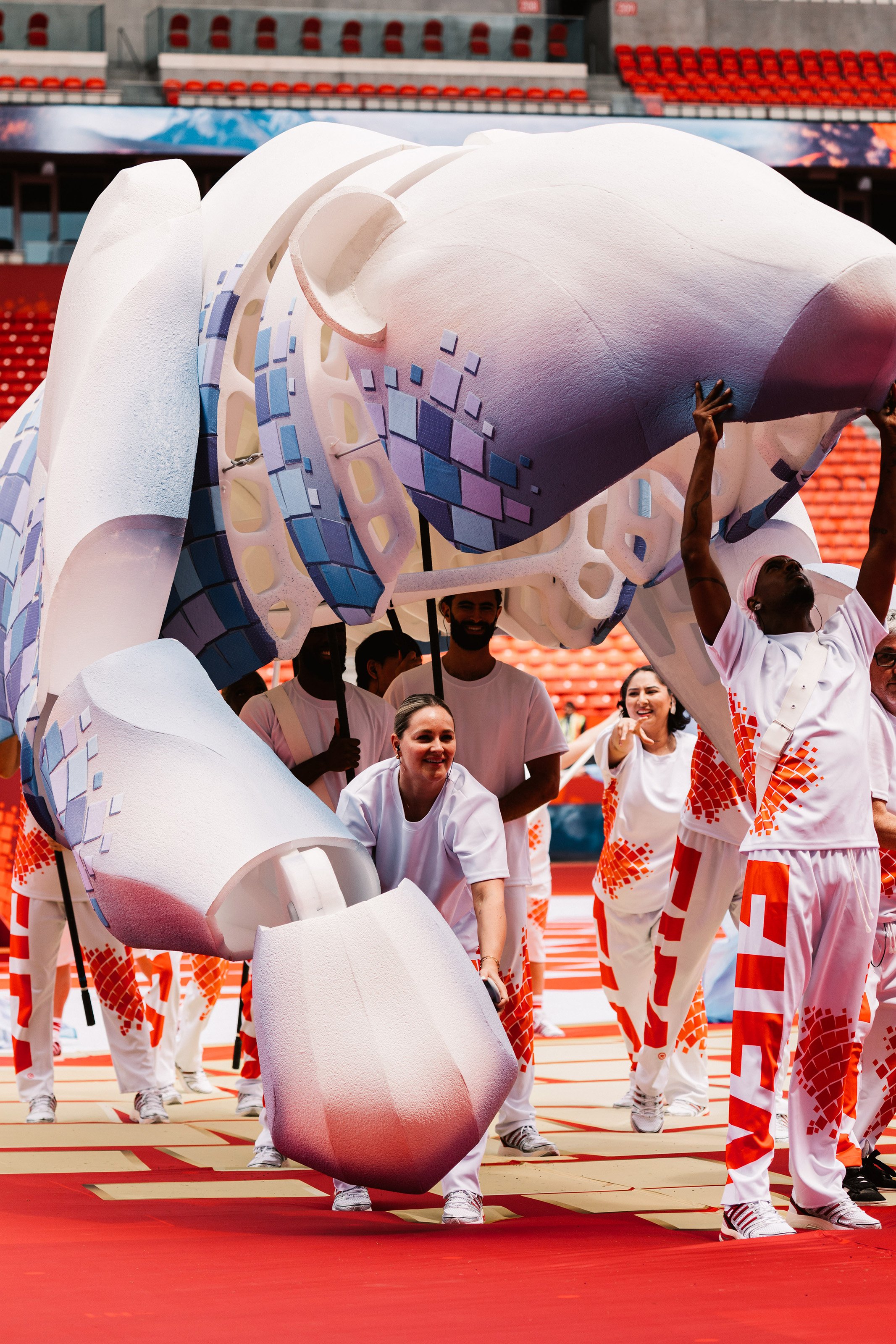 Giant articulated polar bear puppet during rehearsal, carrying the Canadian mosaic graphic language across its sculptural body, designed by Ruby Law