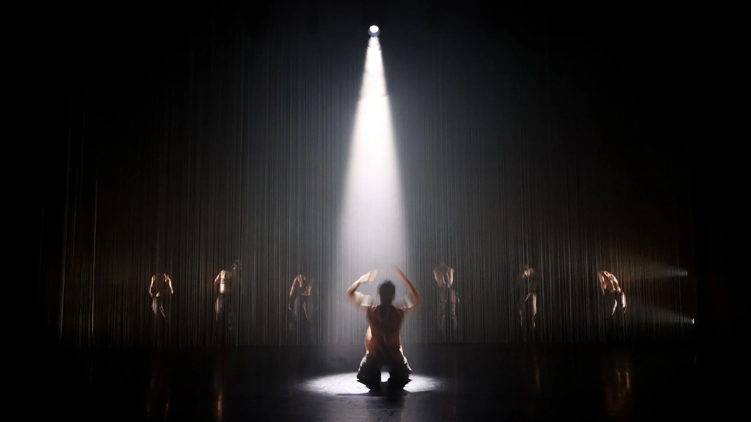 Solo dancer under spotlight framed by layered string curtain threshold in Tellus by Dickson Mbi, contemporary dance set design by London designer Ruby Law.