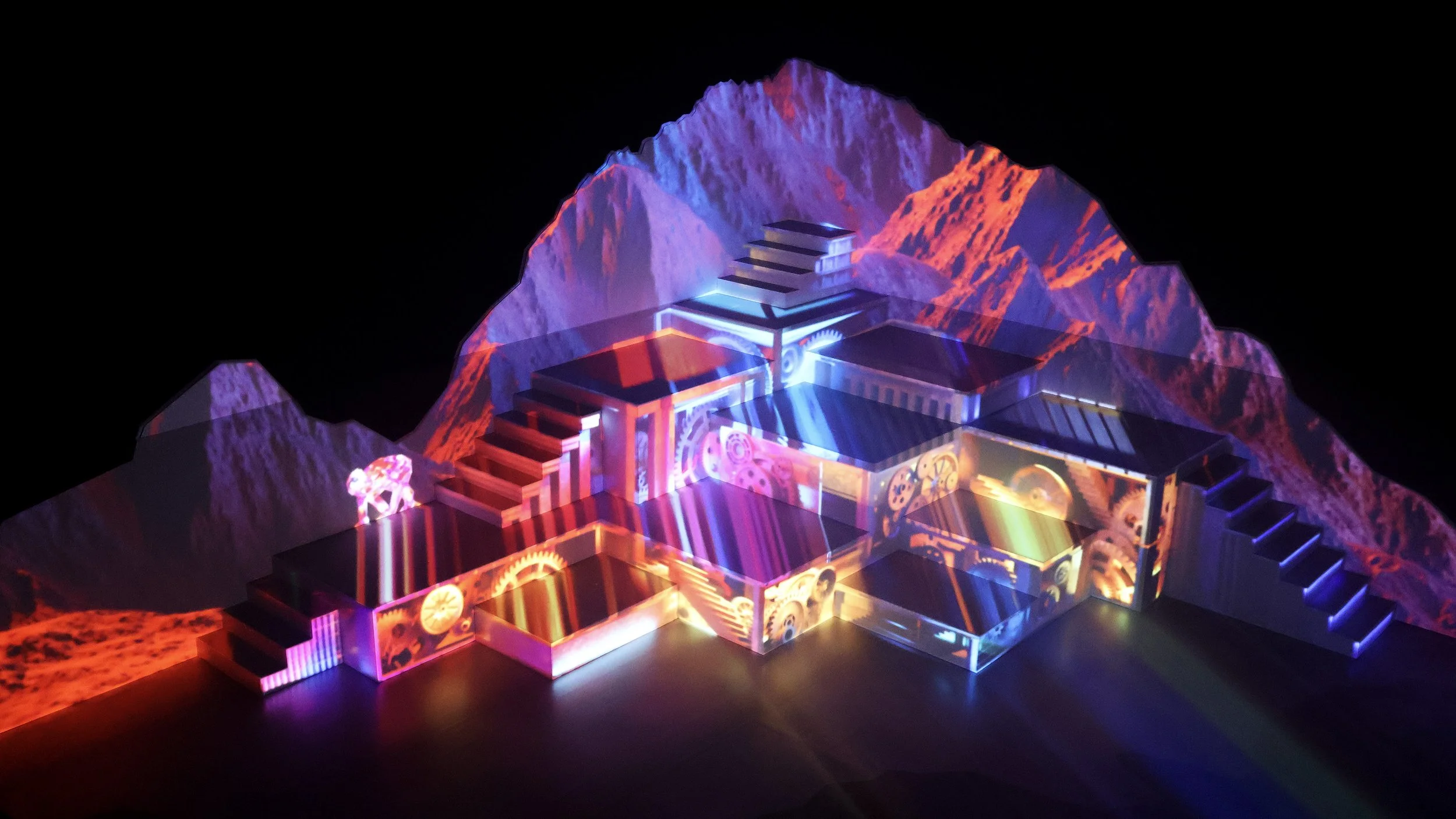 Projection-mapped mountain stage with vivid colour and mechanical imagery, immersive set design by Ruby Law RULA London