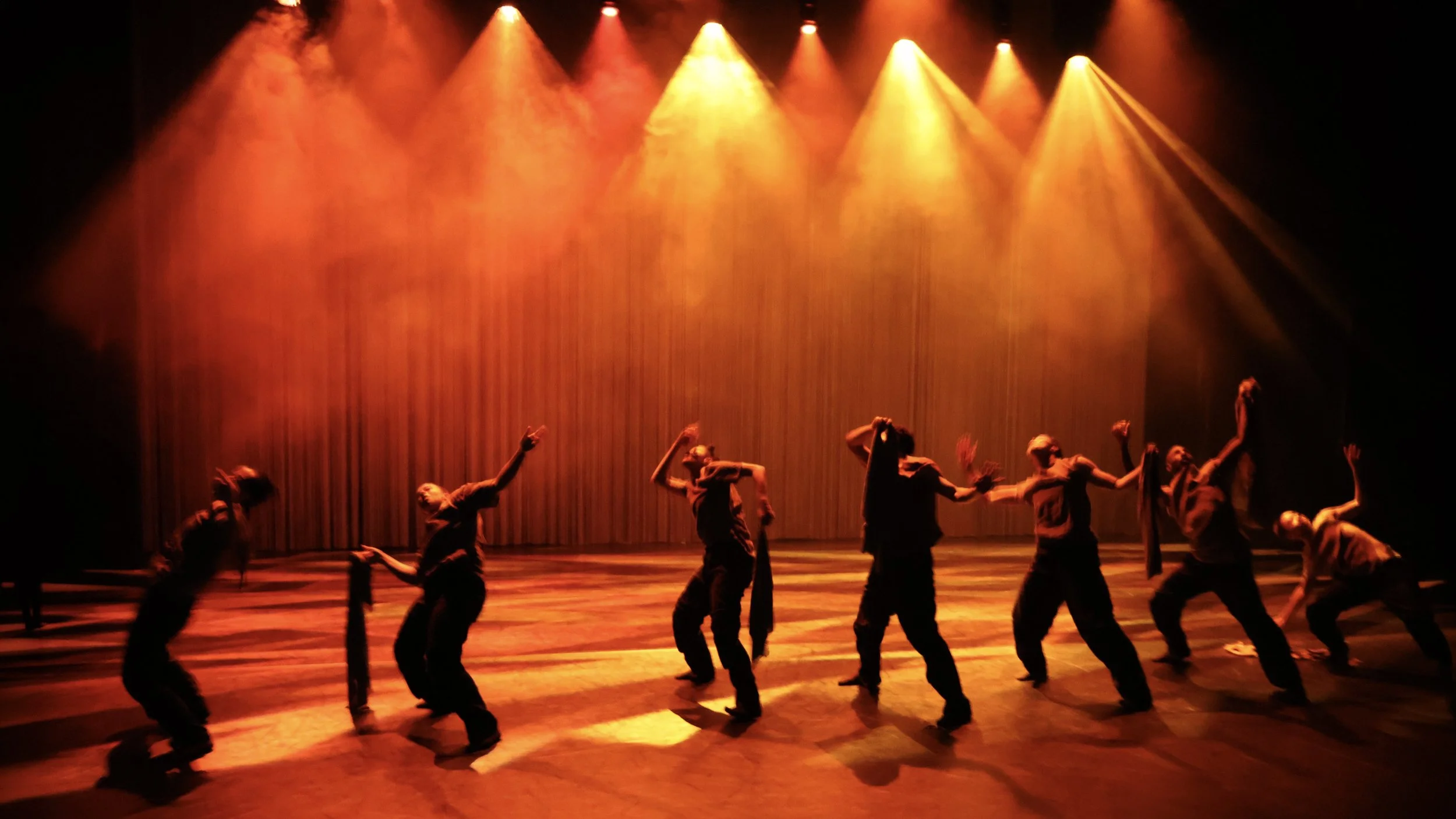 Contemporary dancers in dramatic red lighting with atmospheric haze in Tellus by Dickson Mbi, immersive stage design by London set designer Ruby Law.
