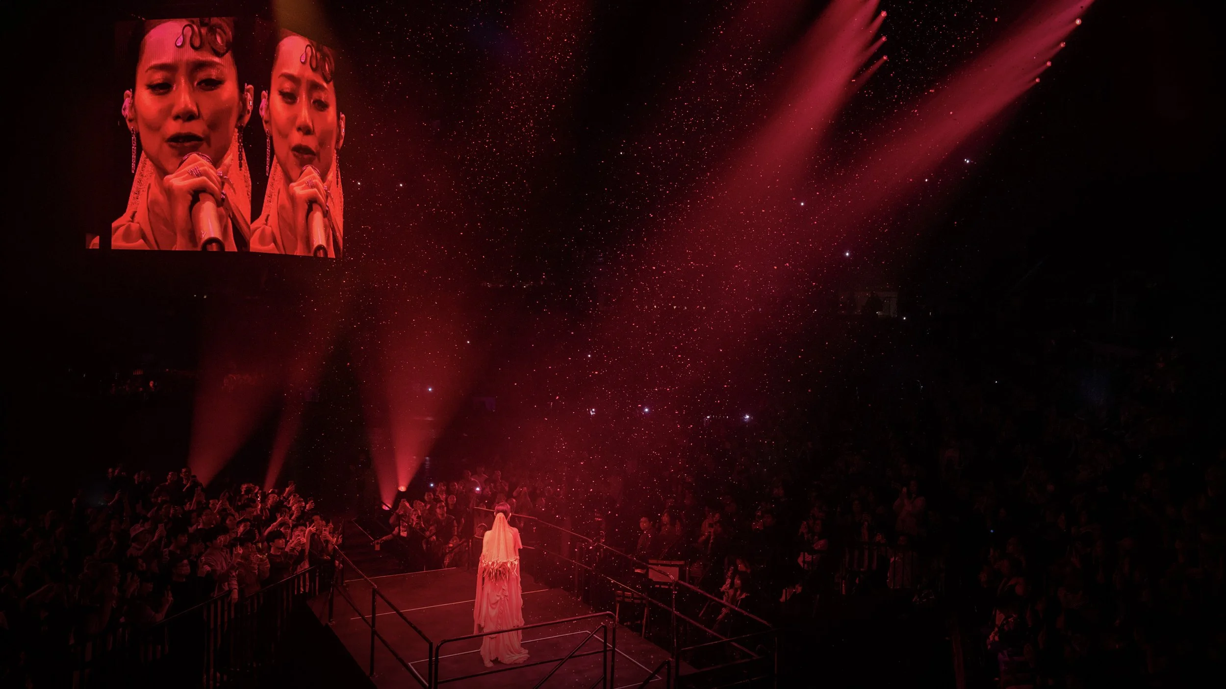 Jace Chan standing on raised platform surrounded by red haze and large LED screen portrait in Jace World concert, stage design by London set designer Ruby Law.