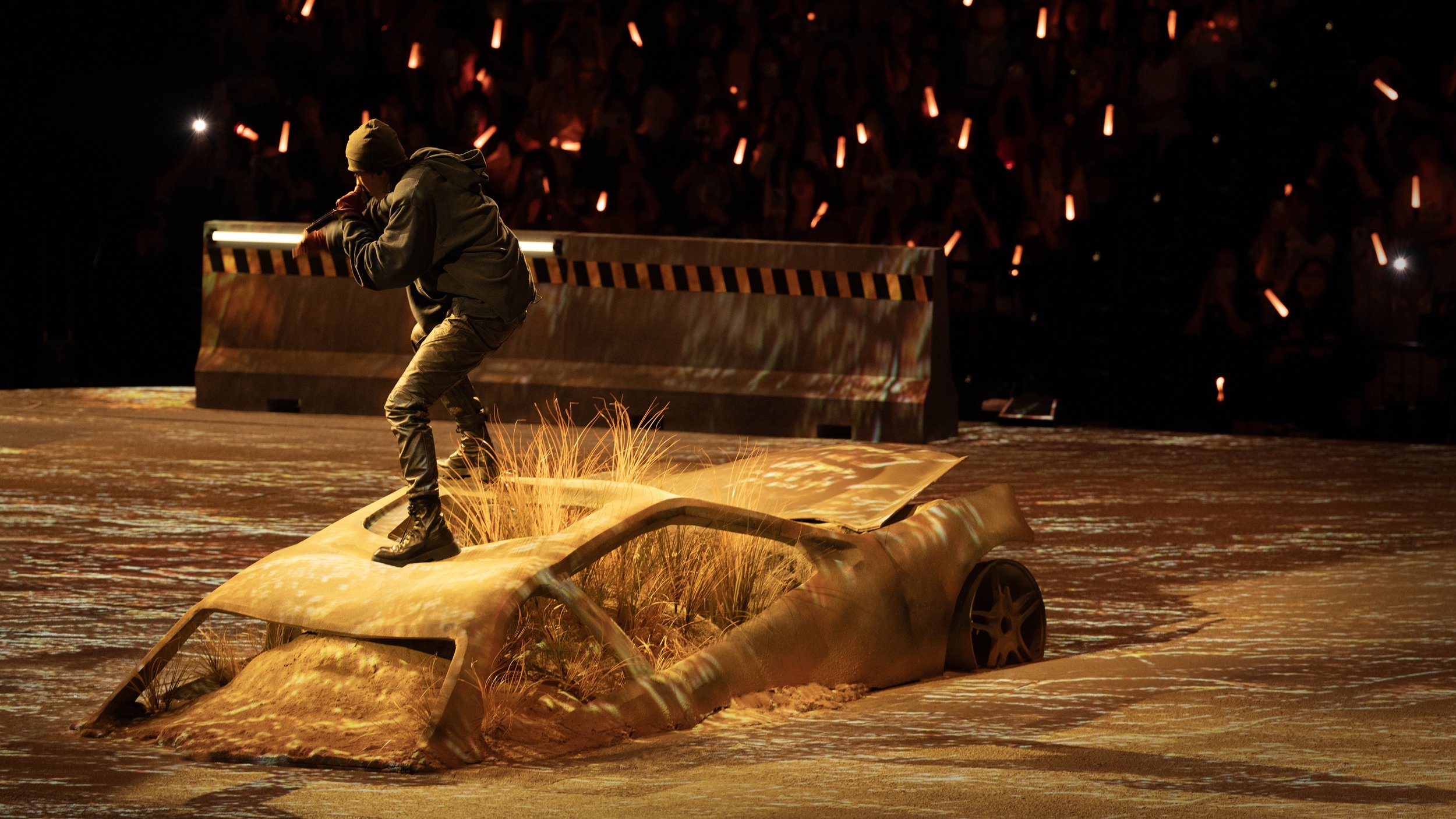 KUN 蔡徐坤 performing on an abandoned car reclaimed by the desert in DEADMAN, concert set design by Ruby Law