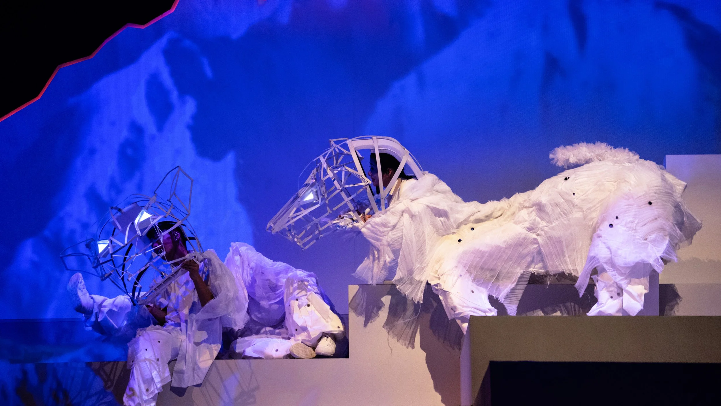 Performer interacting with angular climbing wall set in warm lighting, innovative set design by Ruby Law RULA