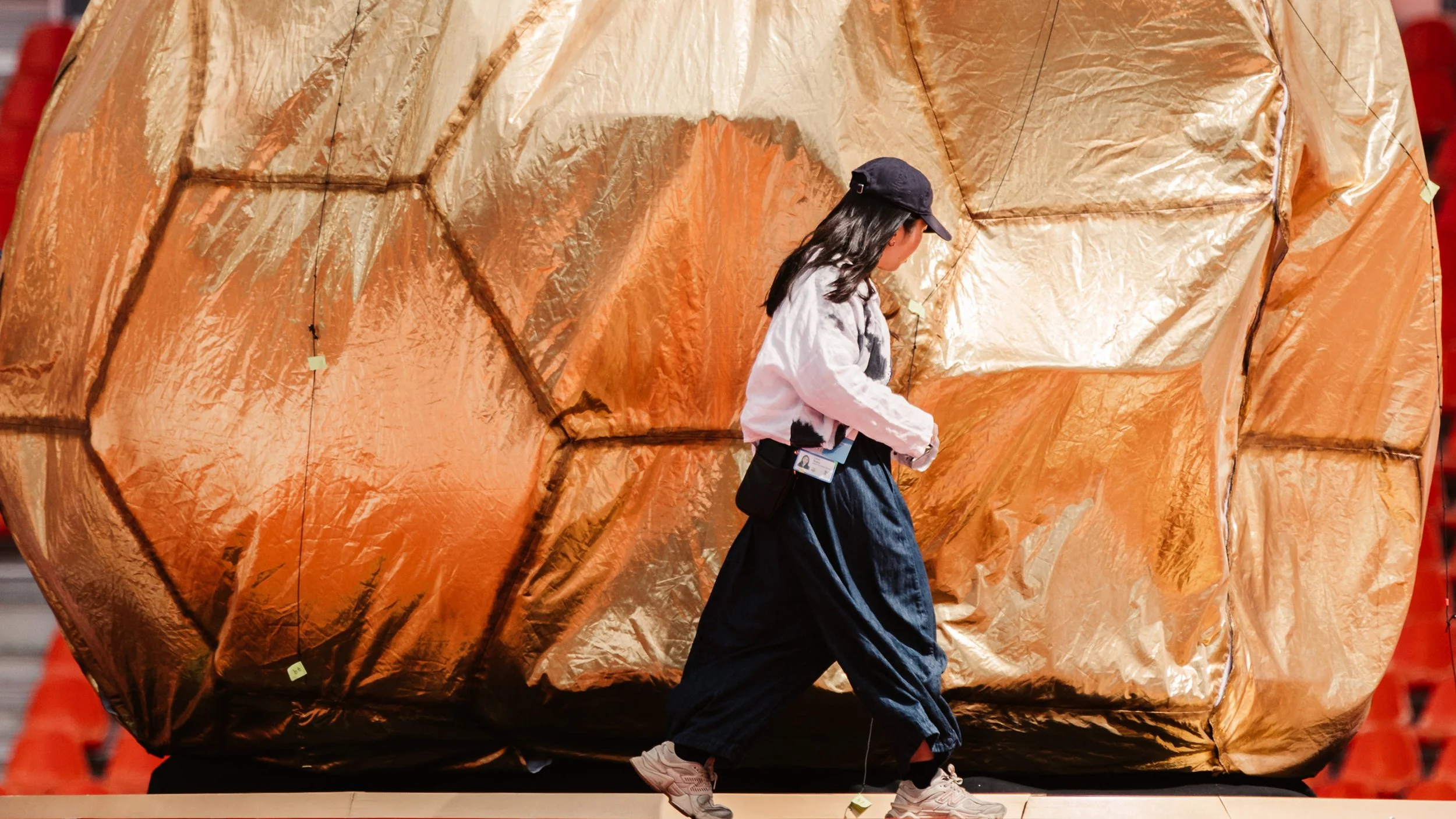 Final adjustments to the Golden Ball beneath its reflective gold inflatable skin during technical rehearsal.