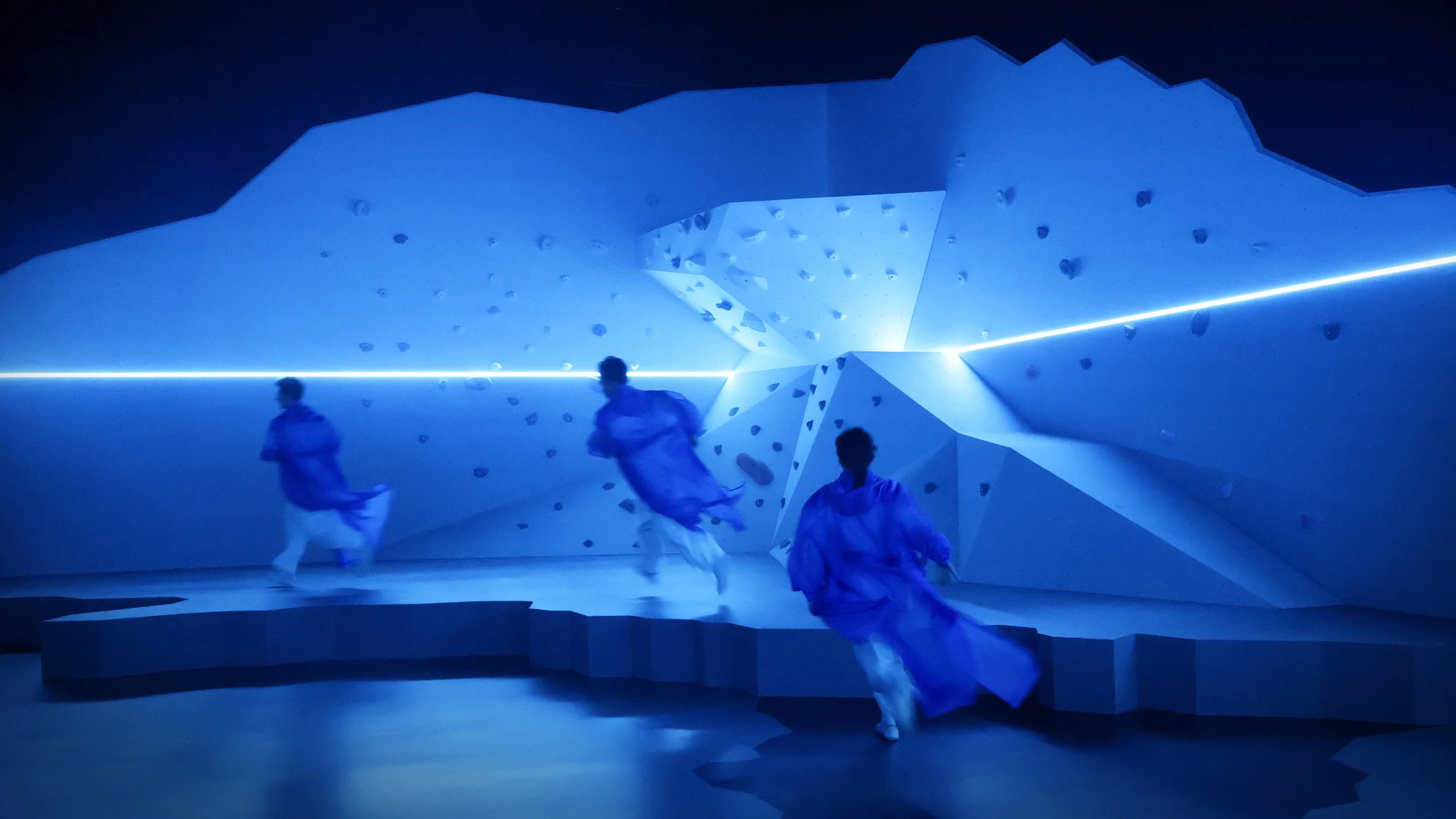 Blue-lit immersive mountain environment with performers in motion, cool set design by Ruby Law RULA London