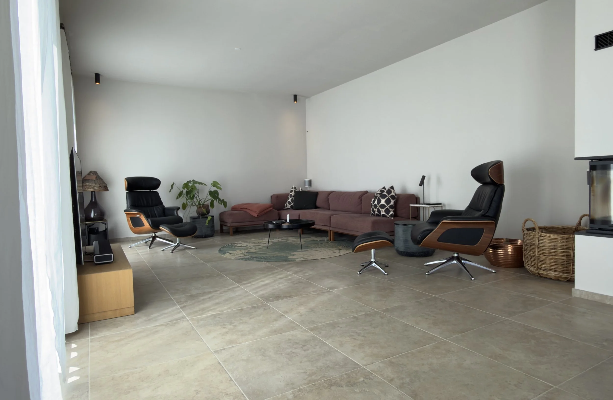 Large living room with flat screen TV, Apple TV box, Sonos surround sound system and wood stove.