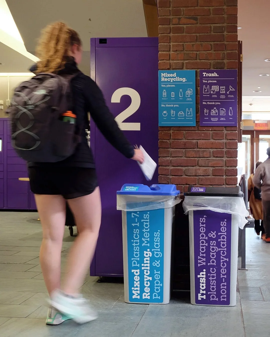 student throwing paper into a recycling bin