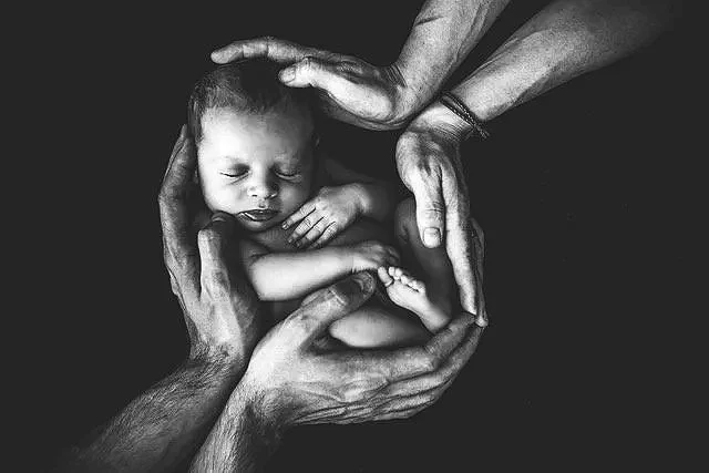 BIPOC hands surrounding baby.jpg