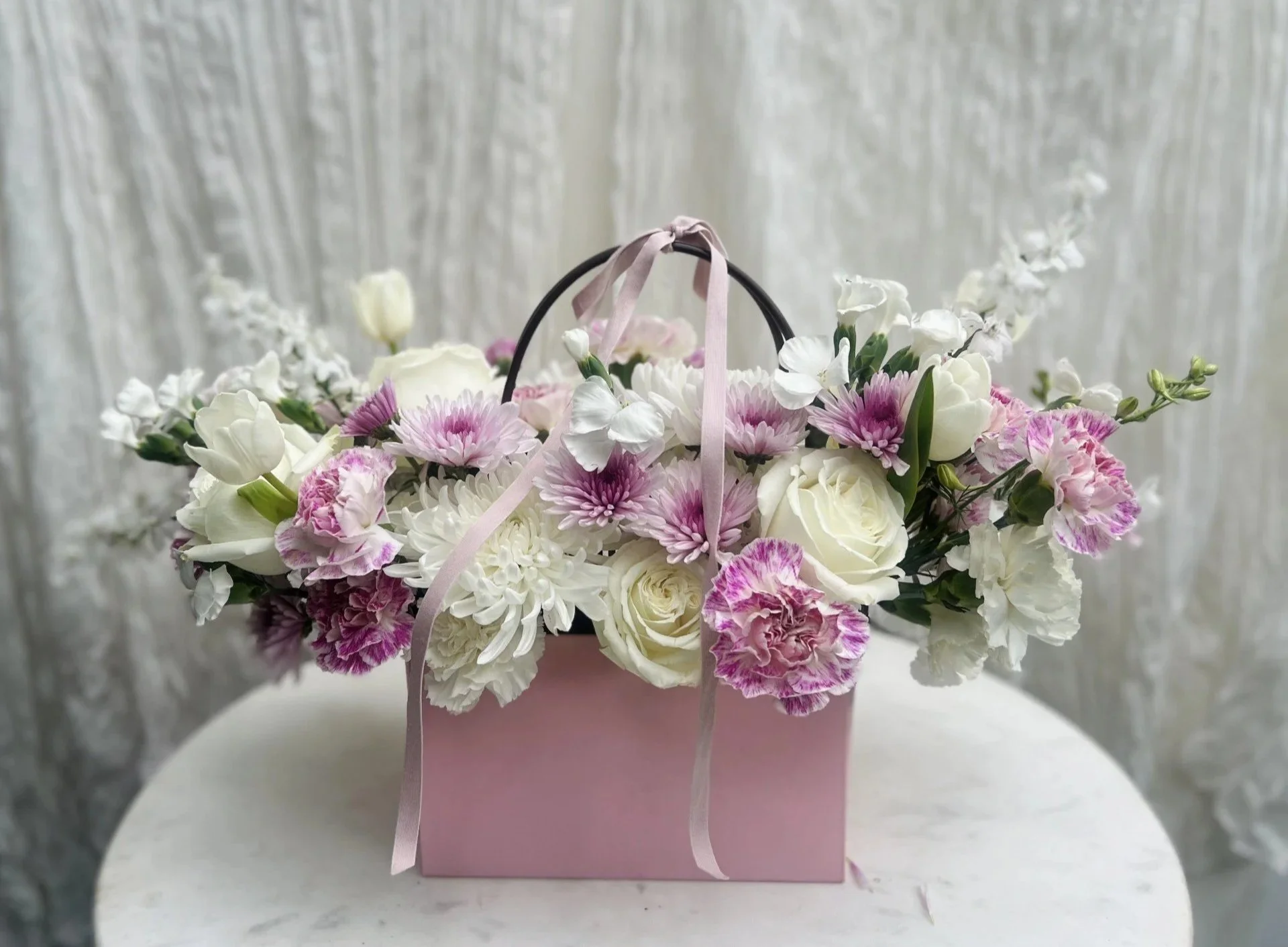 Luxury white and pink flower arrangement in a green keepsake tote bag featuring seasonal garden roses, premium blooms, and lush greenery