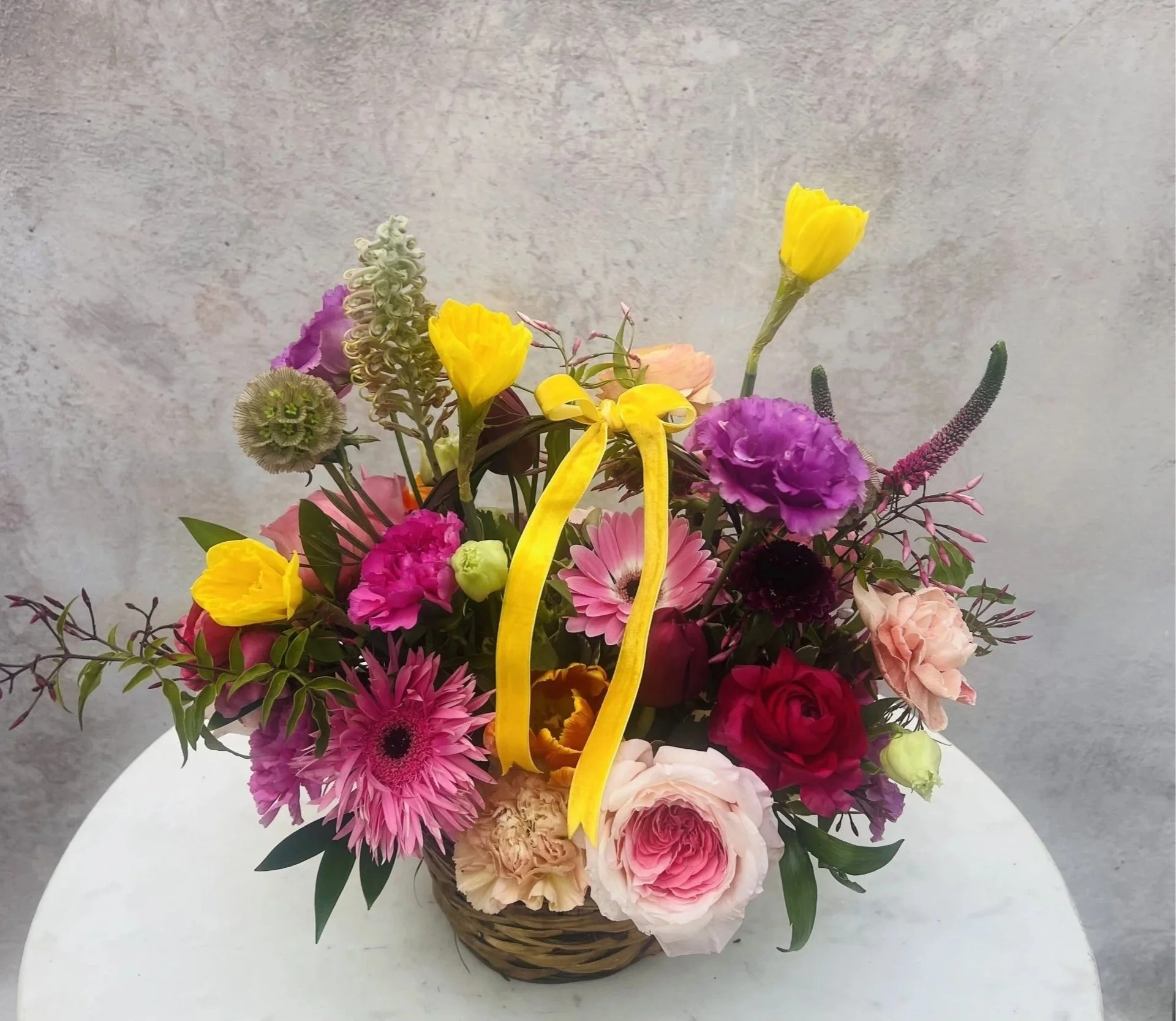 Vibrant spring flower arrangement in woven basket with premium seasonal flowers
