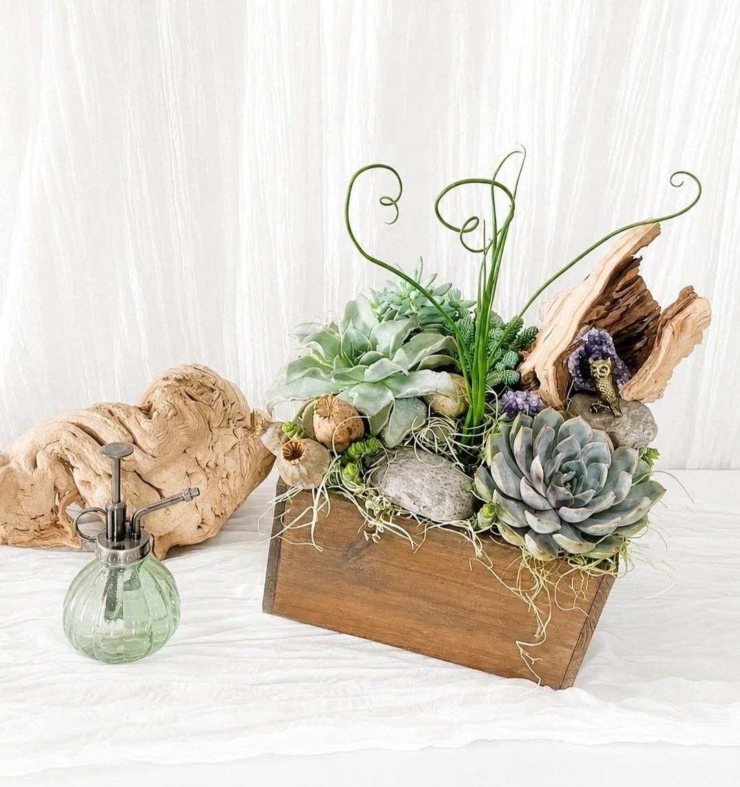 Front view of a luxury succulent planter in a handmade square wood box featuring assorted succulents, lush ferns, polished river rock, and genuine amethyst crystals.