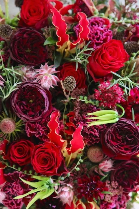 Close-up of lush red floral arrangement with rich, dramatic tones
