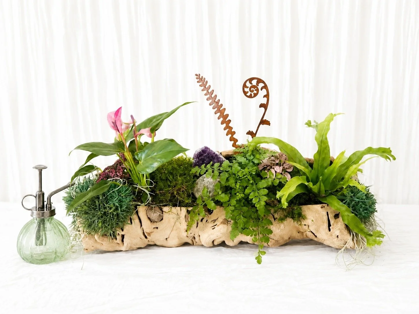 Luxury driftwood living planter featuring pink anthurium, maidenhair fern, preserved moss, amethyst crystal, decorative metal fern accents, and a vintage glass plant mister.