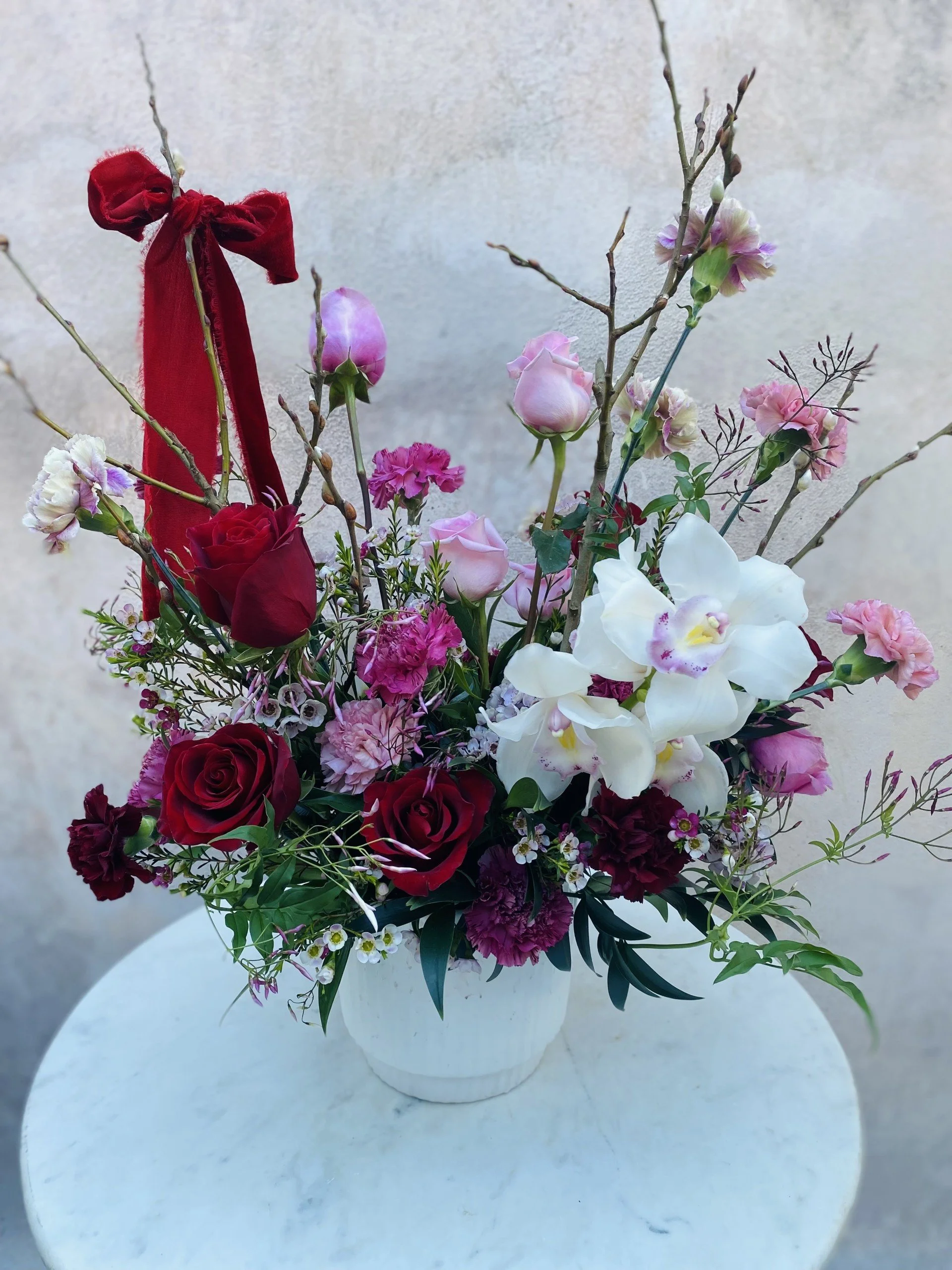 Romantic red, pink, and white flower arrangement featuring orchids and premium seasonal blooms in a lush garden-style design, front view