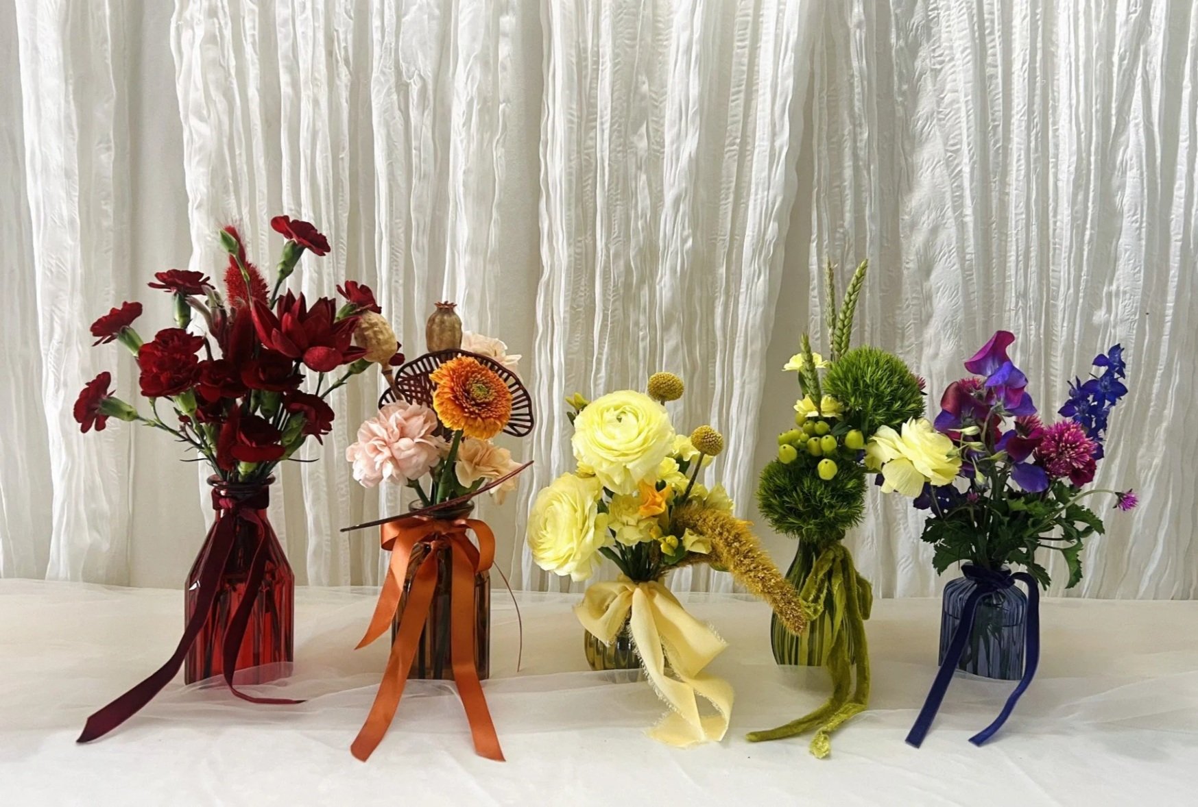 Rainbow Pride bud vase collection featuring individual clear glass bud vases filled with premium seasonal flowers in red, orange, yellow, green, blue, and violet