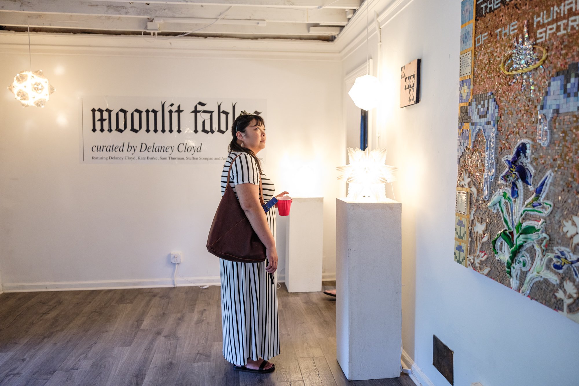 woman looks at art during opening reception for show moonlit fables at friday the gallery in decatur, ga