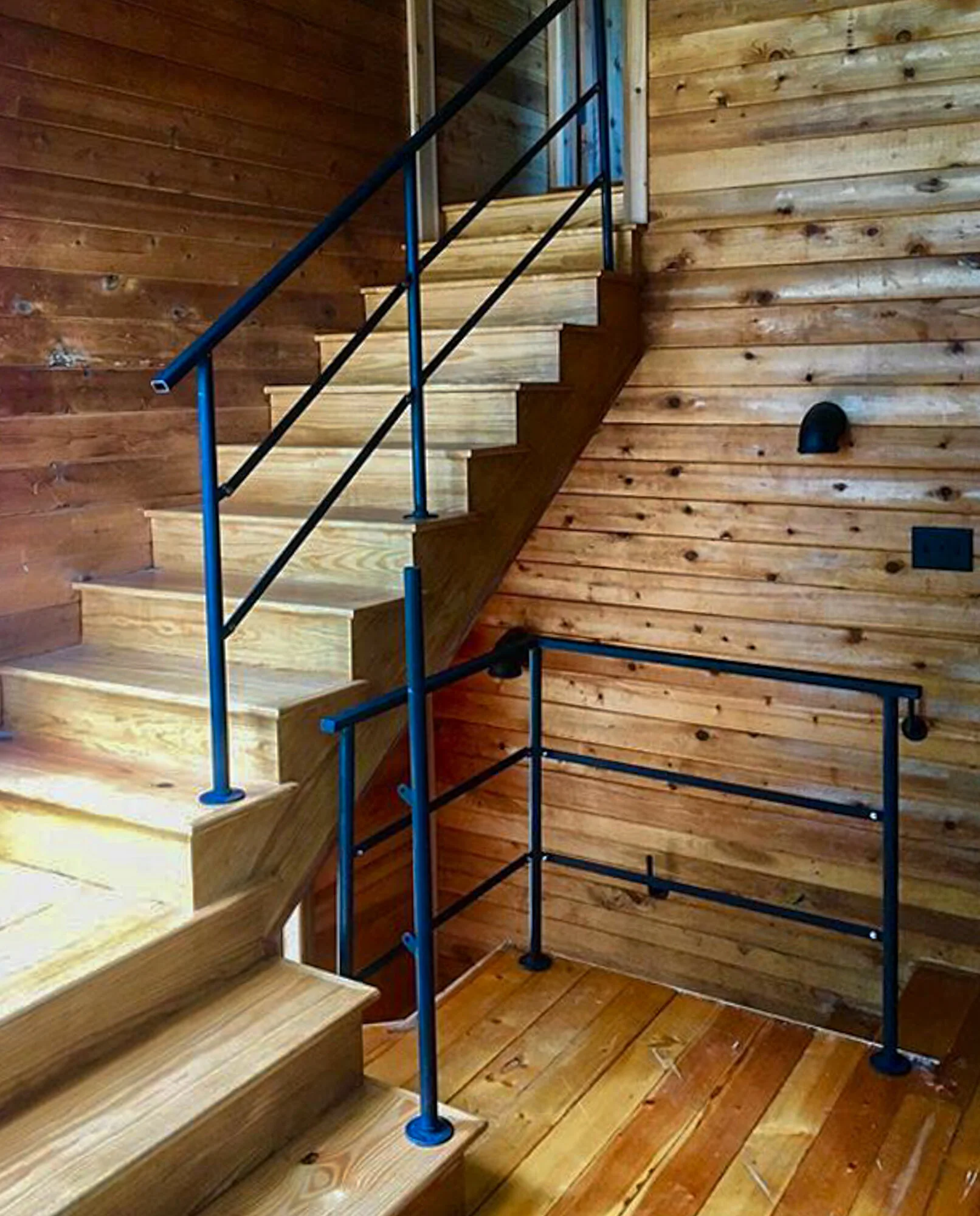 image of a wooden interior space with a post, handrail, and guardrail fabricated by smithworks iron and design