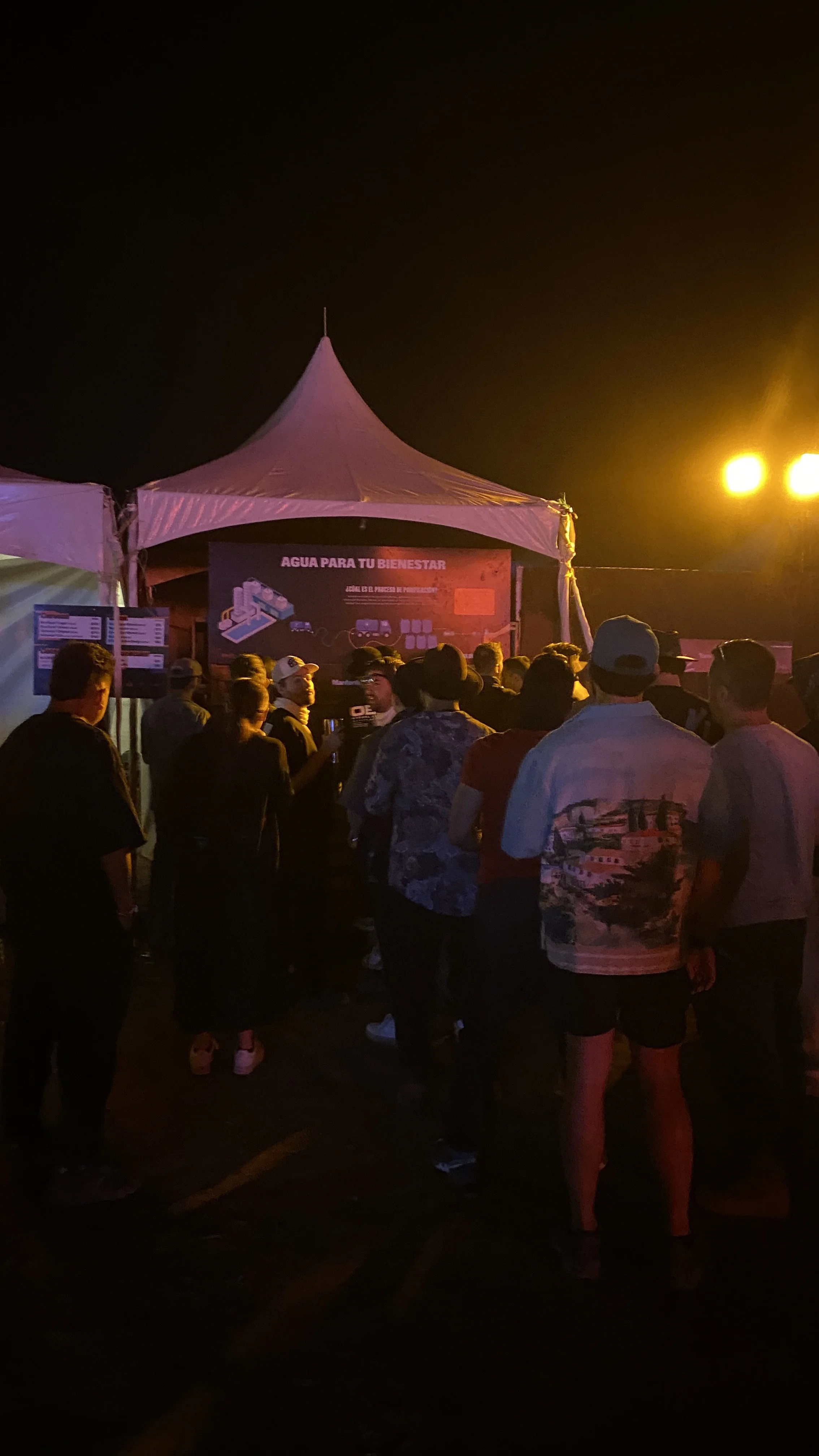 Grupo de personas en festival Akamba hidratándose en el bebedero