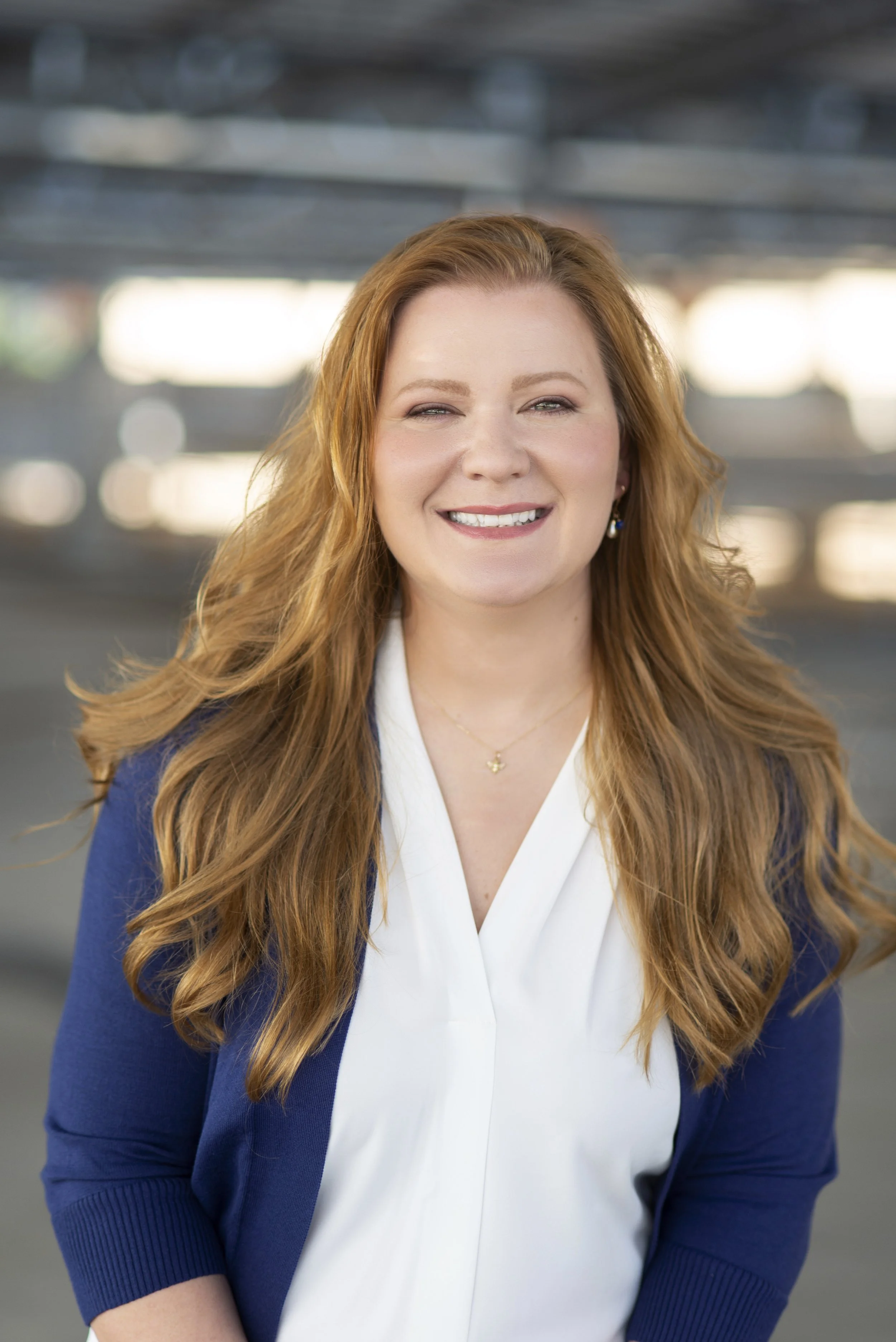 Anna Khandrueva, an IFS therapist, is smiling at the camera, wearing a white top and a blue cardigan.