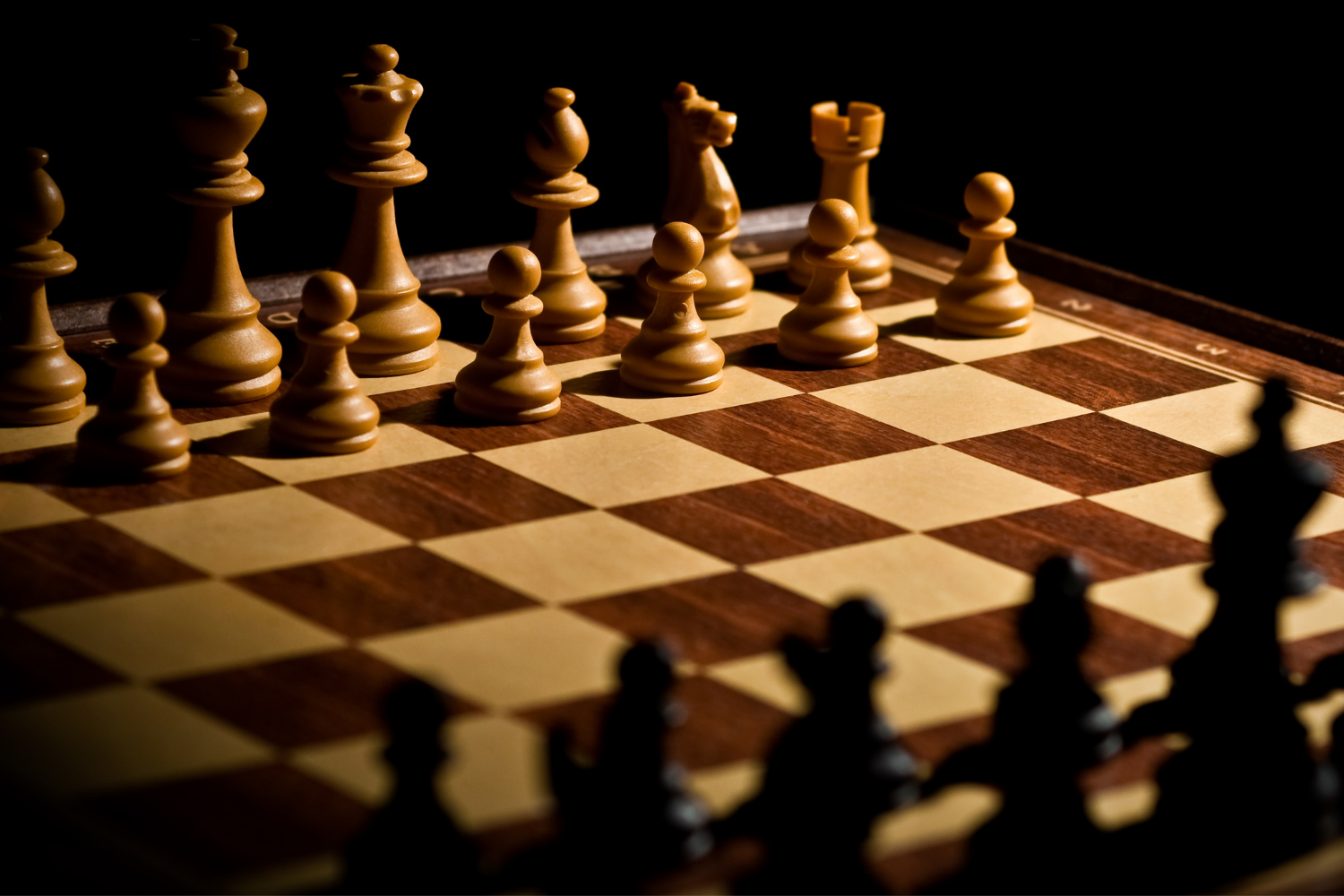 Wooden chess board, with pieces set up on either side for the beginning of a game.