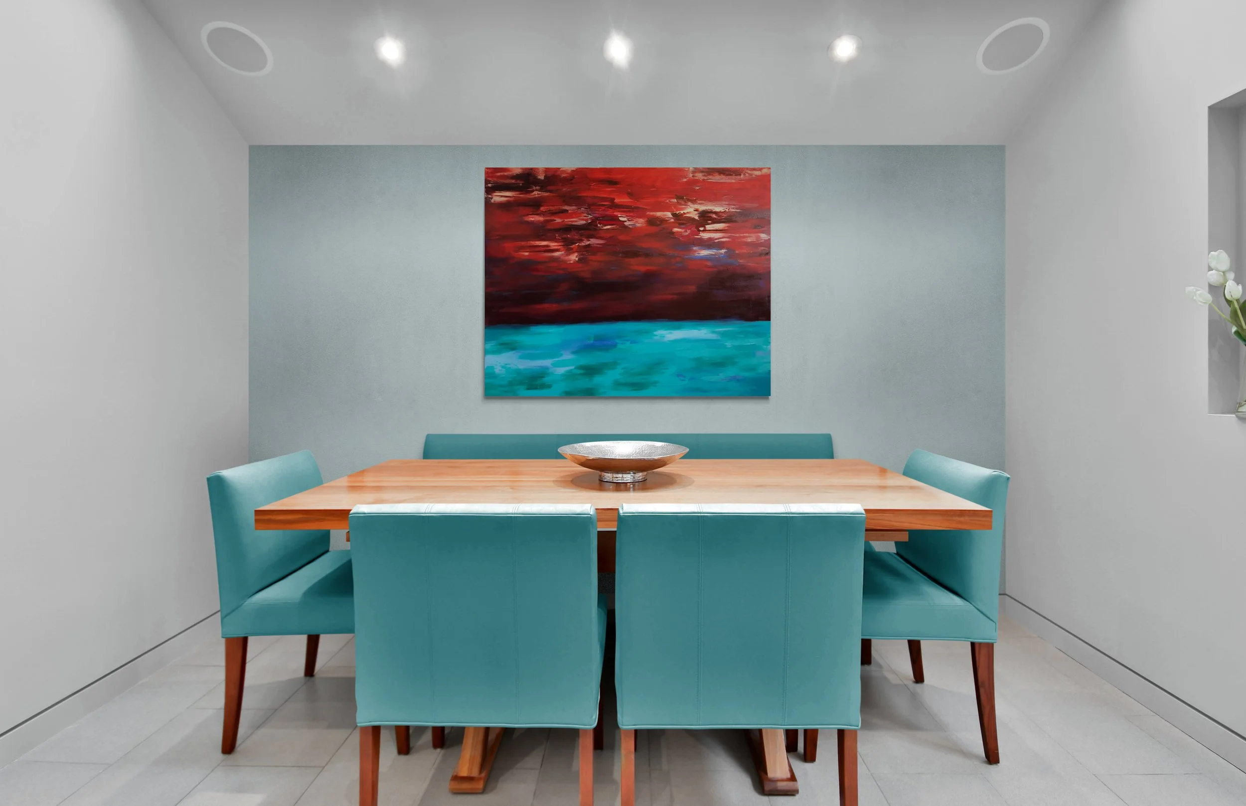 Modern dining room with light gray walls, teal chairs around a wooden table, and an abstract painting with red, brown, and blue tones on the wall.