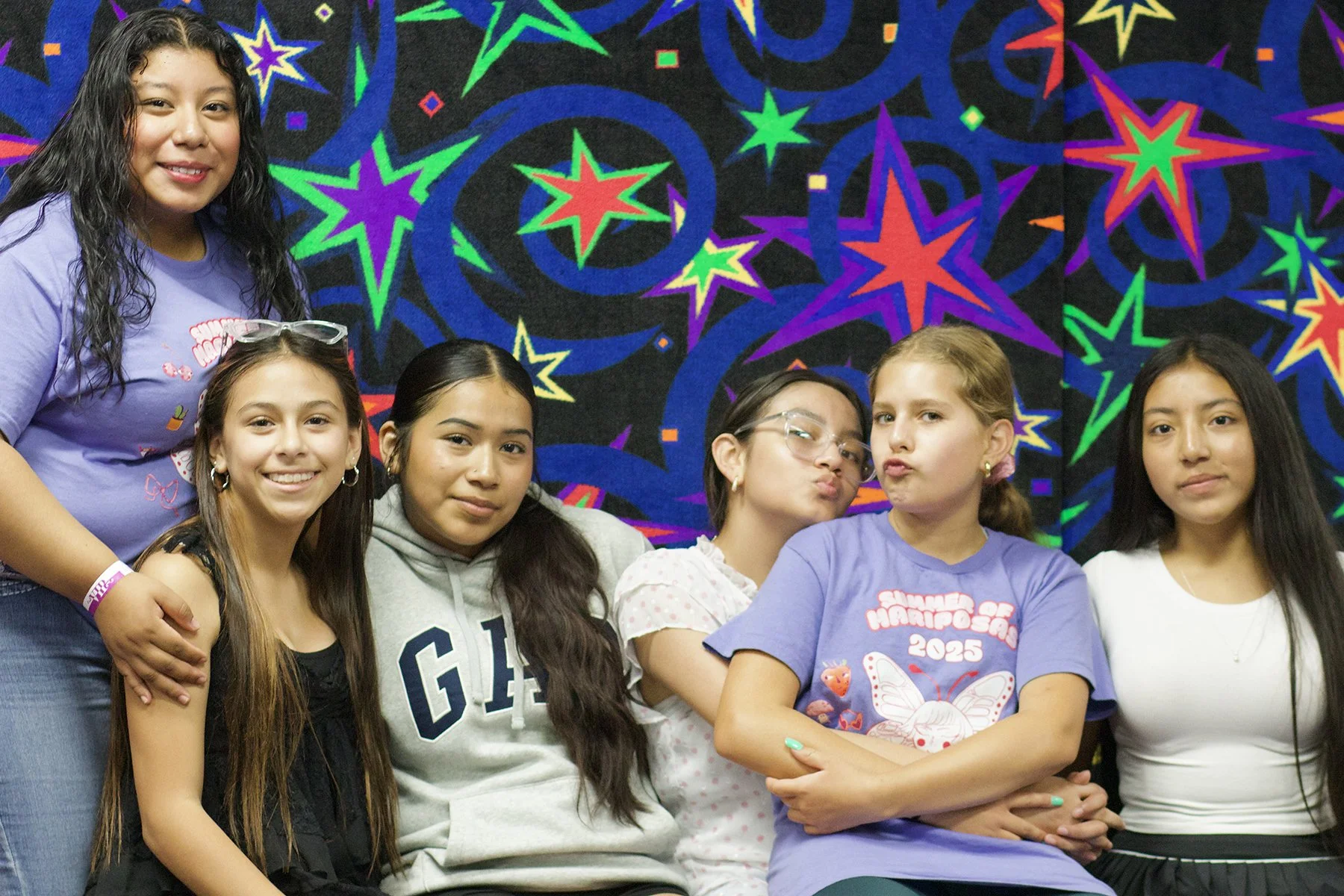 Group of Latina girls sitting against a neon backdrop