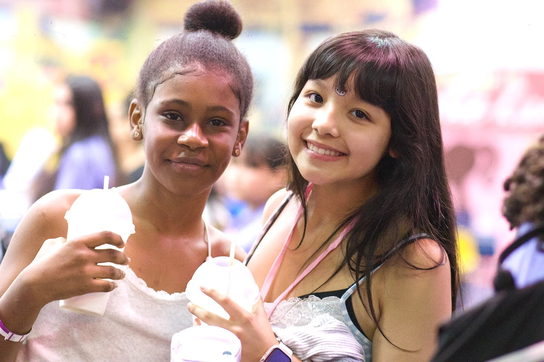 Two Latina girls smiling at the camera holding slurpees