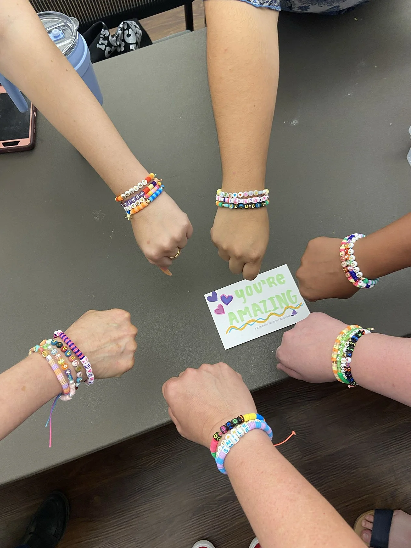 Group of girls hands wearing bracelets holding note cards