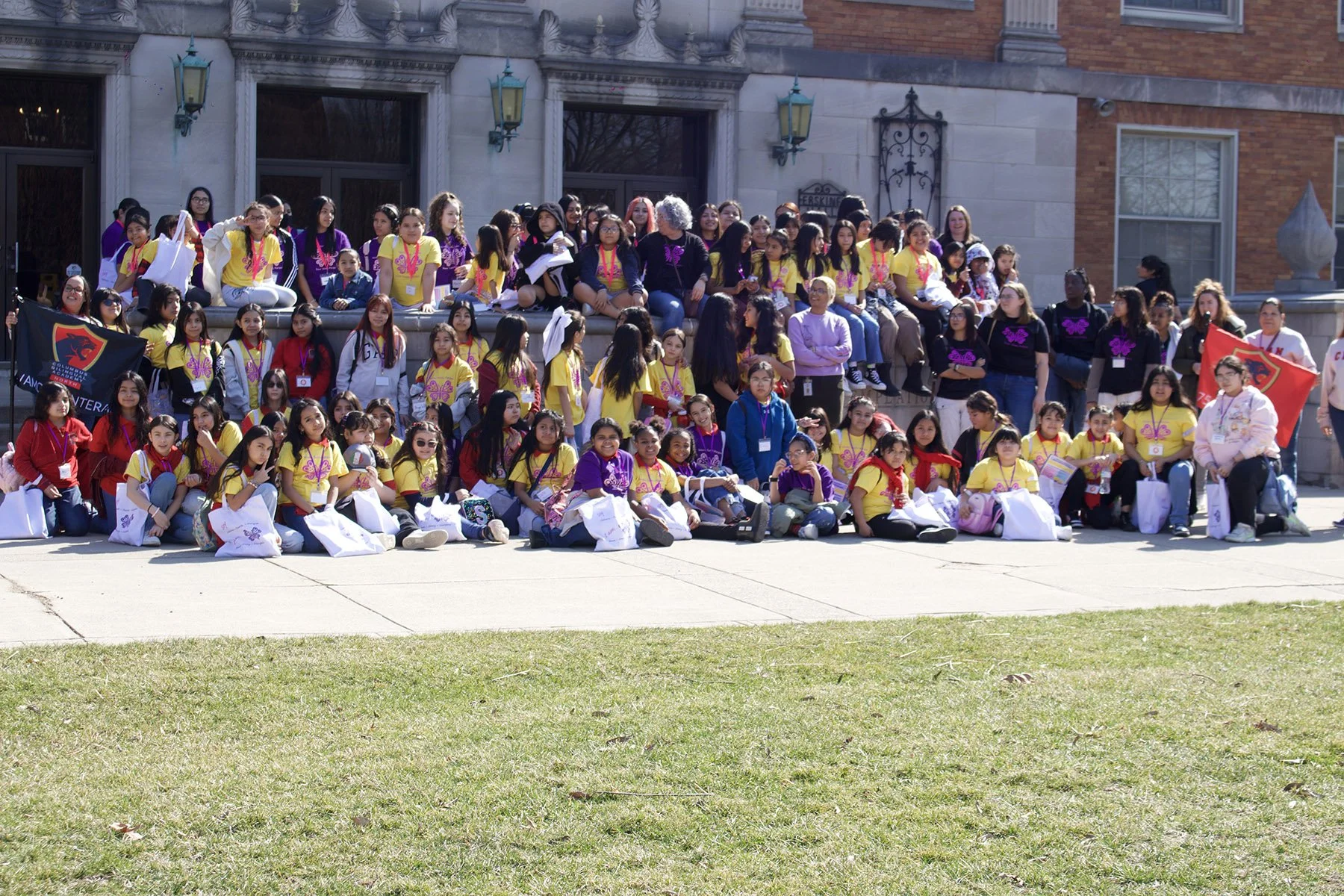 Large group of latina girls sitting in front of an ornate building