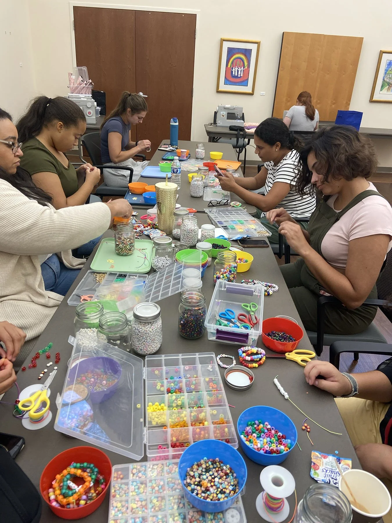 Group of women sitting around a table making beaded bracelets