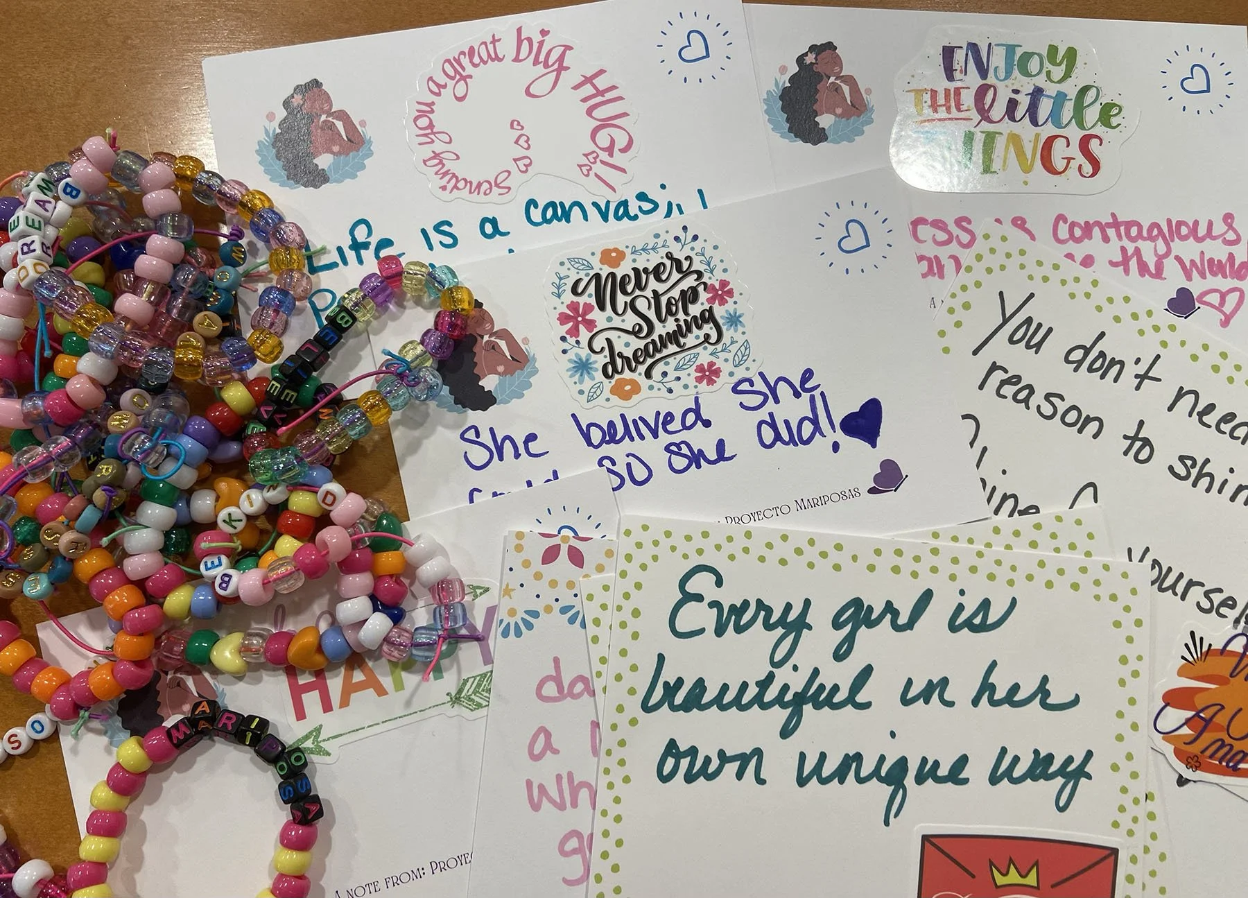 Pile of colorful beaded bracelets with note cards of uplifting messages