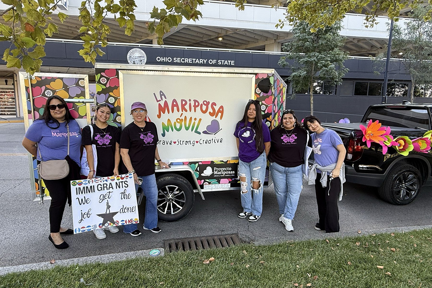 Group of smiling latinas standing around the art mobile