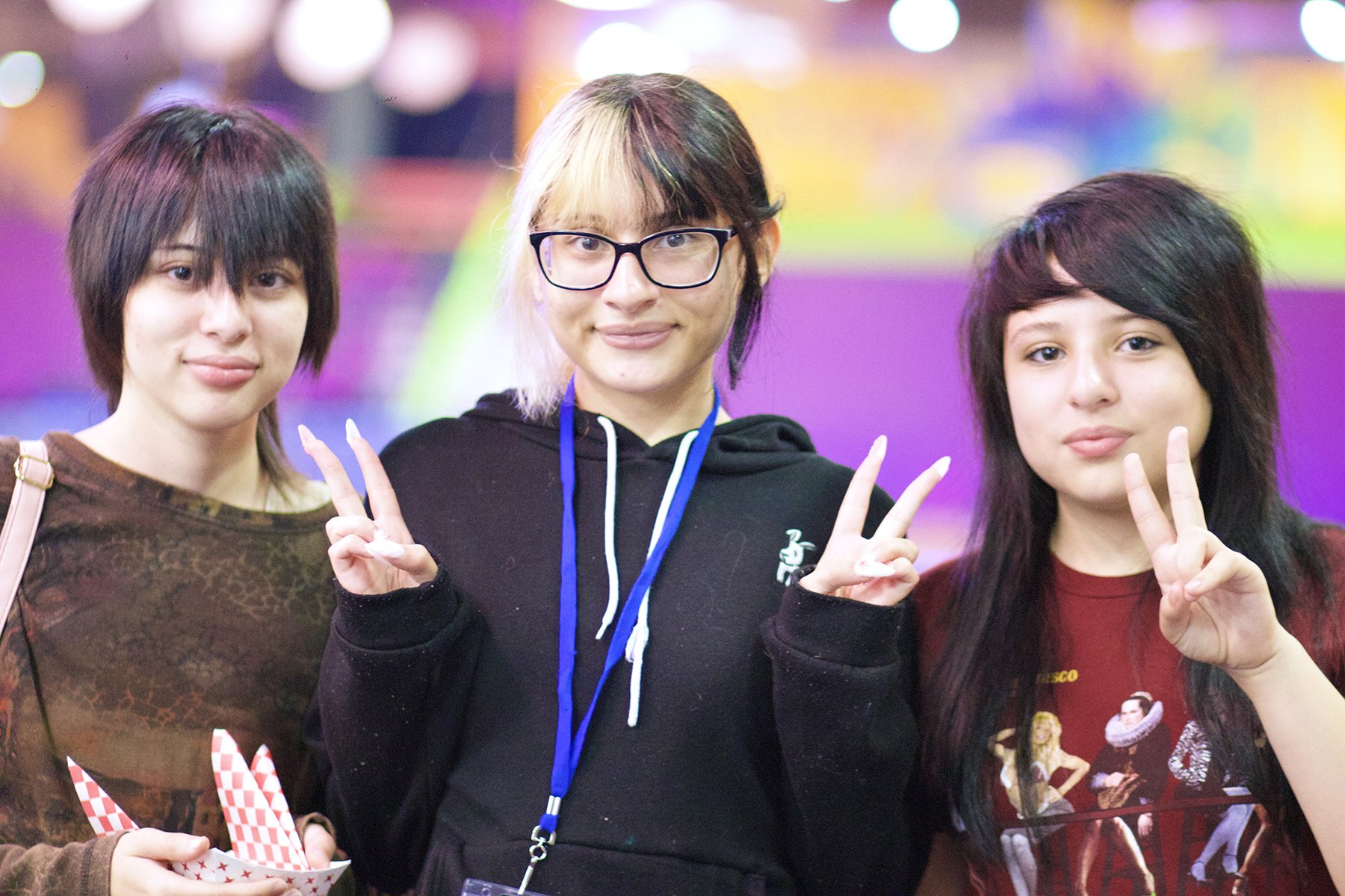 Three Latina girls giving peace signs and smiling at the camera