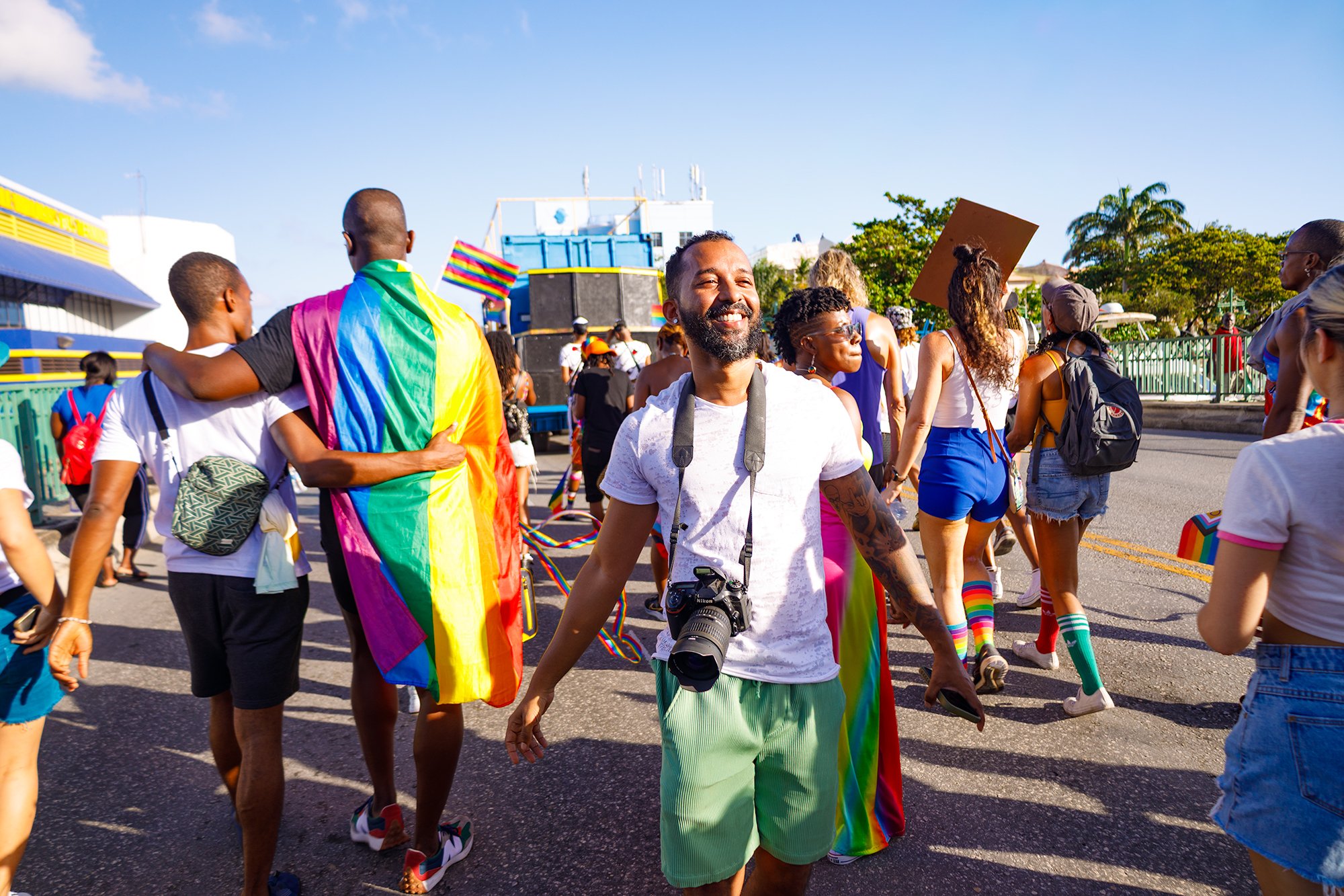 Participants carrying rainbow flags during the Barbados Pride parade through Bridgetown, photographed in a candid documentary style by Alyson Holder.
