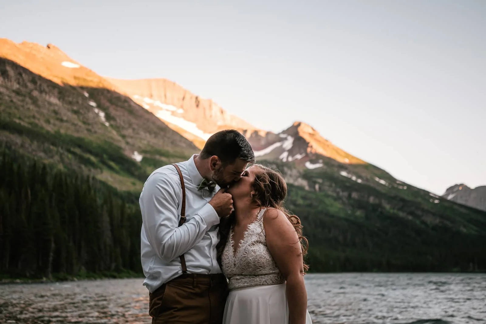 Groom pulls bride in for a kiss by Bowman Lake.