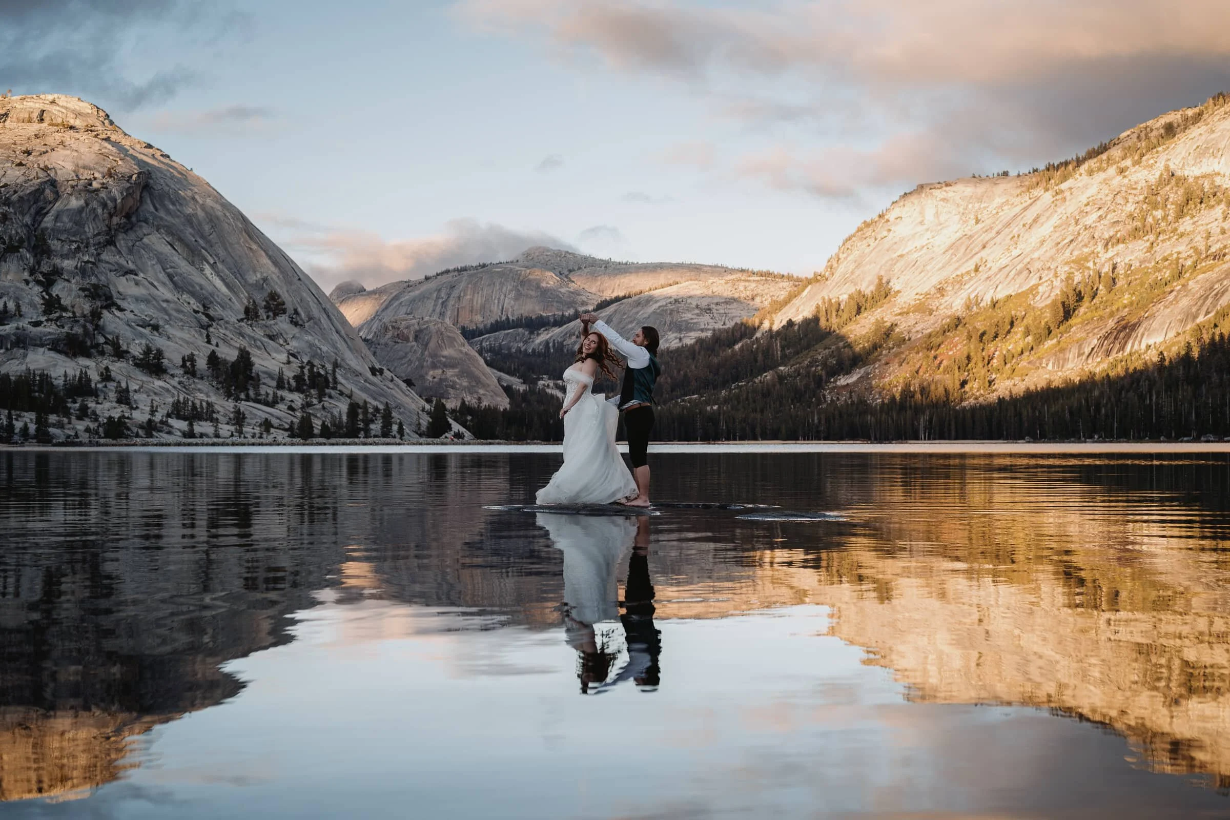 newlyweds dance on a rock in the middle of tenaya lake at sunset