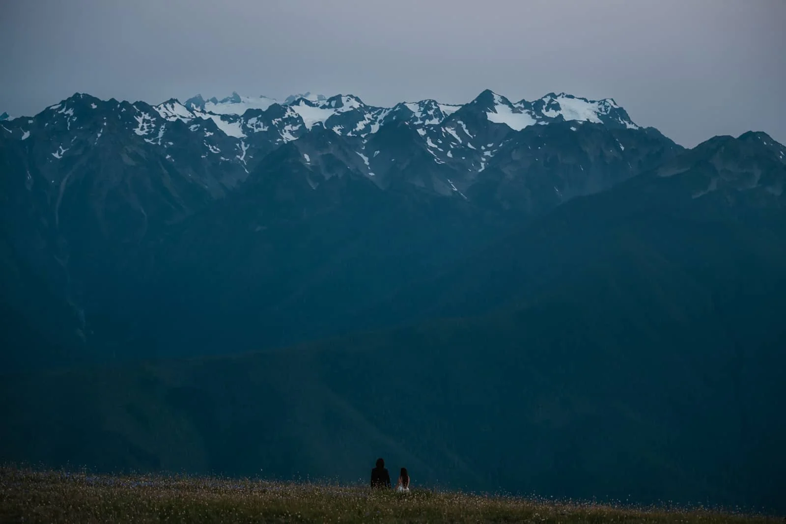 couple walks towards the blue mountains of the olympic range